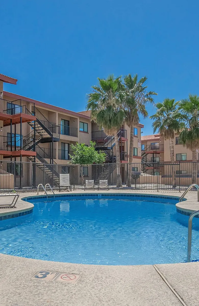 pool with lounge chairs and three story apartment buildings in the back