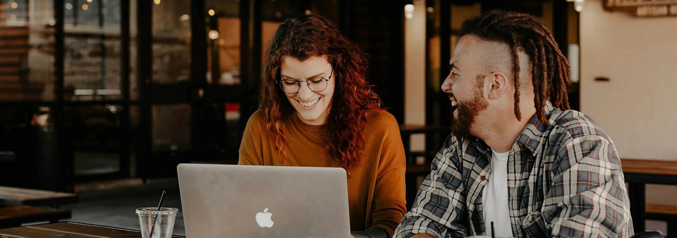 man and woman sitting at a coffee shop working on a laptop
