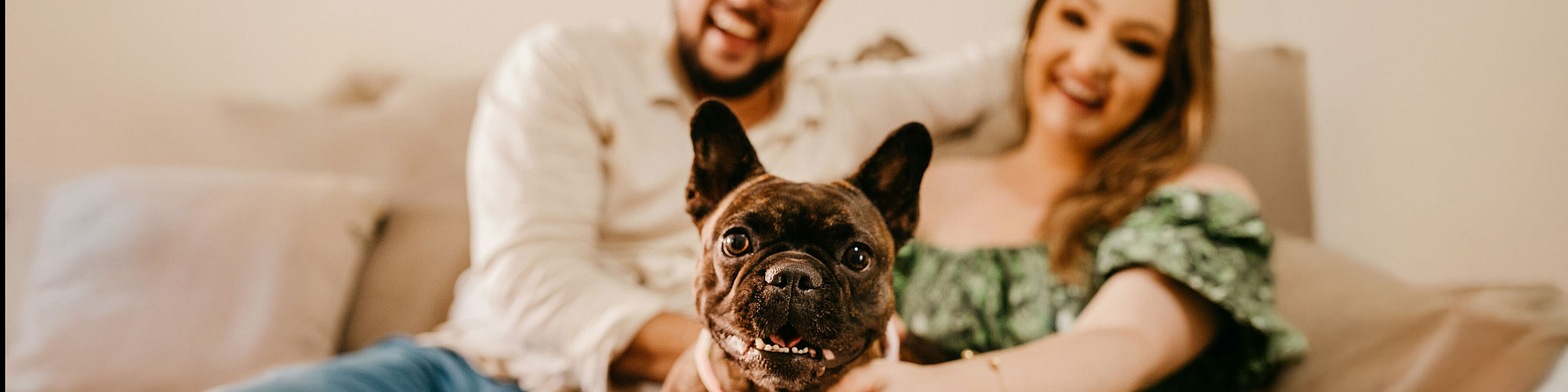 two people sitting in their sofa with a small dog