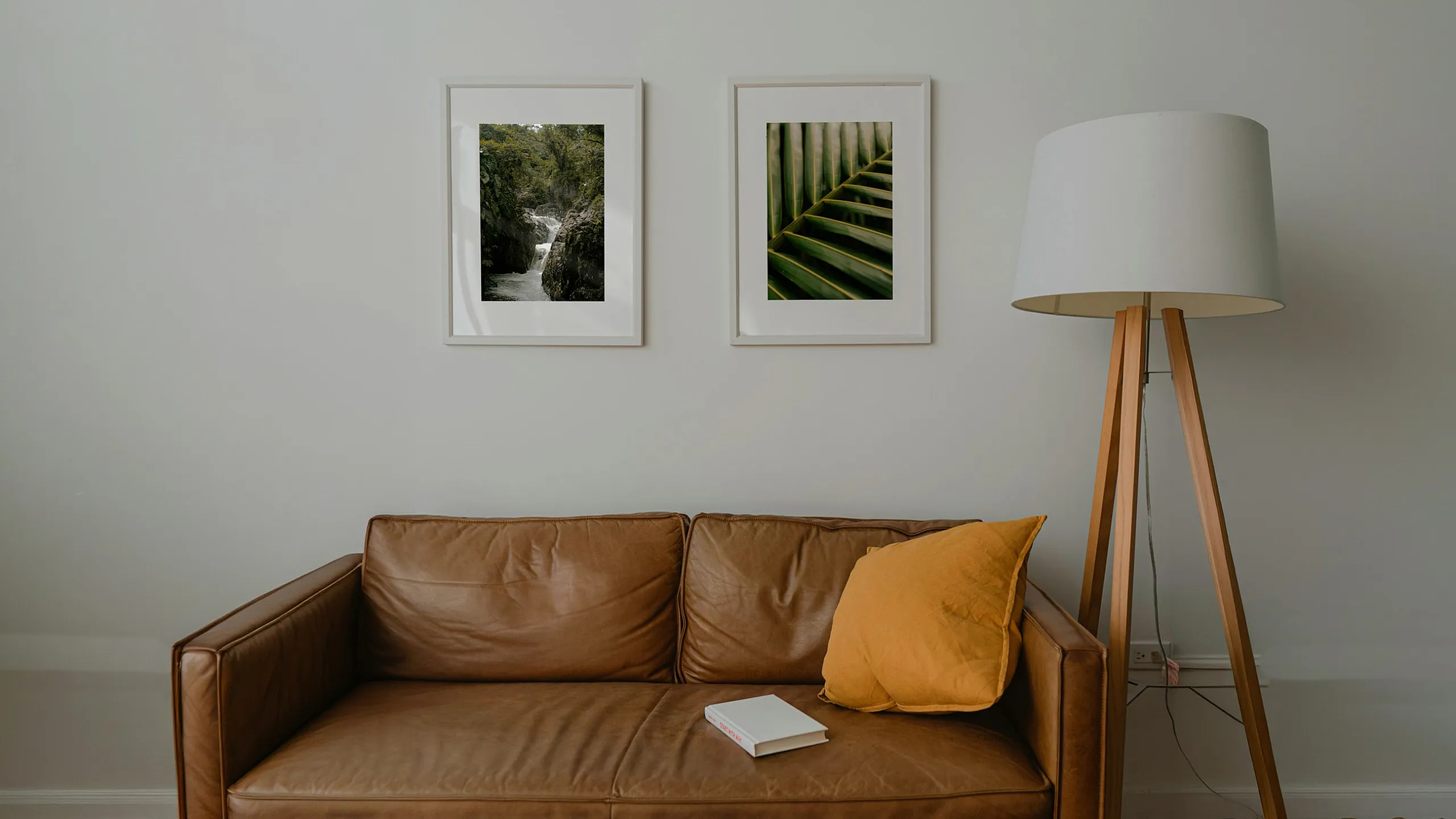 brown leather sofa with accent pillow and tripod lamp