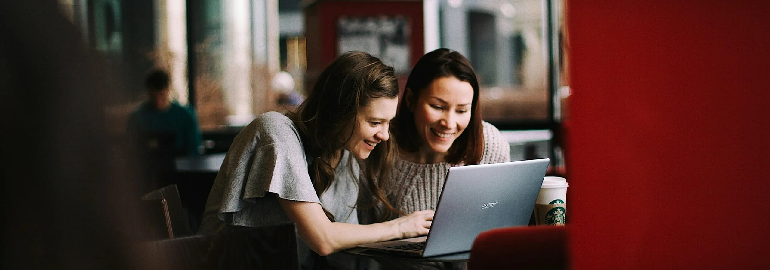 two women looking at a computer in a cafe