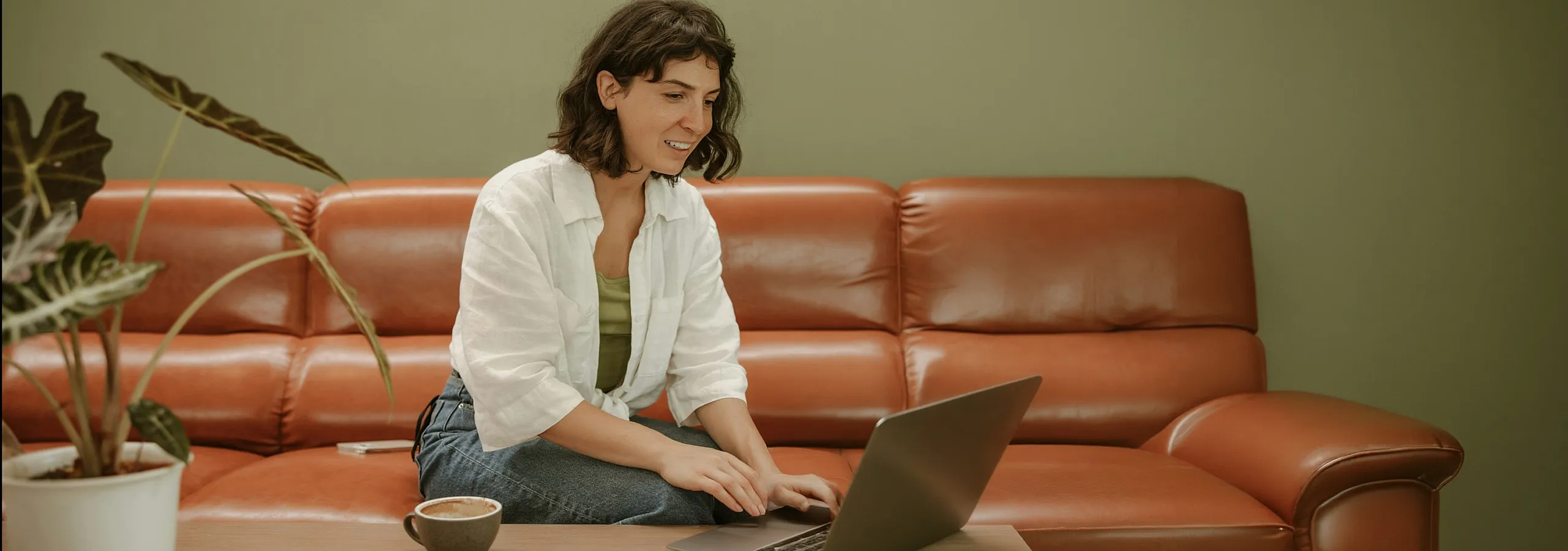 woman sitting on leather sofa while working on computer