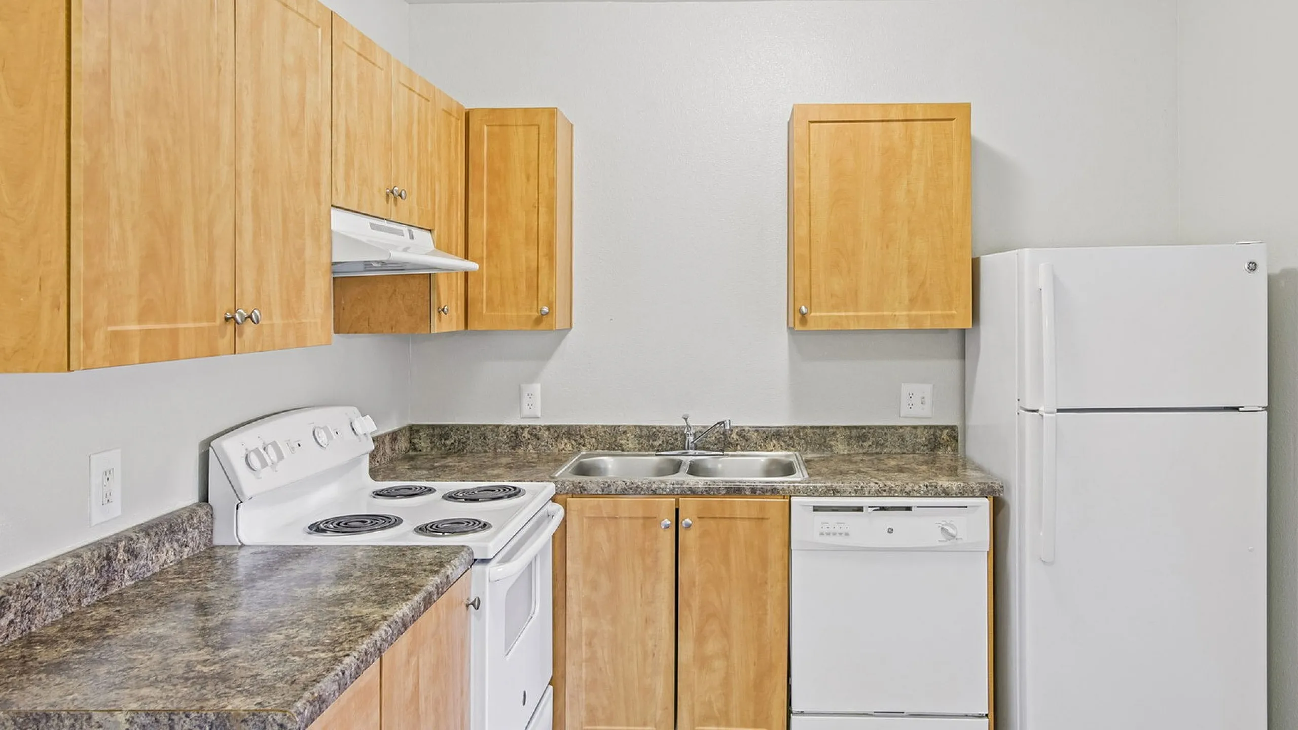 kitchen in the 1x1 floorplan at ventura villas with white appliances and woord cabinets