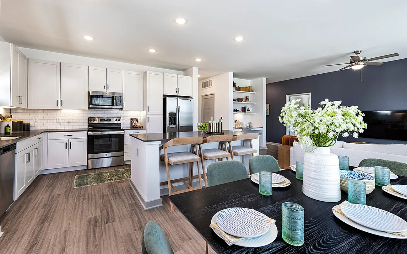 Modern kitchen with sleek appliances, bar seating, and stylish dining table set for guests with elegant decor.