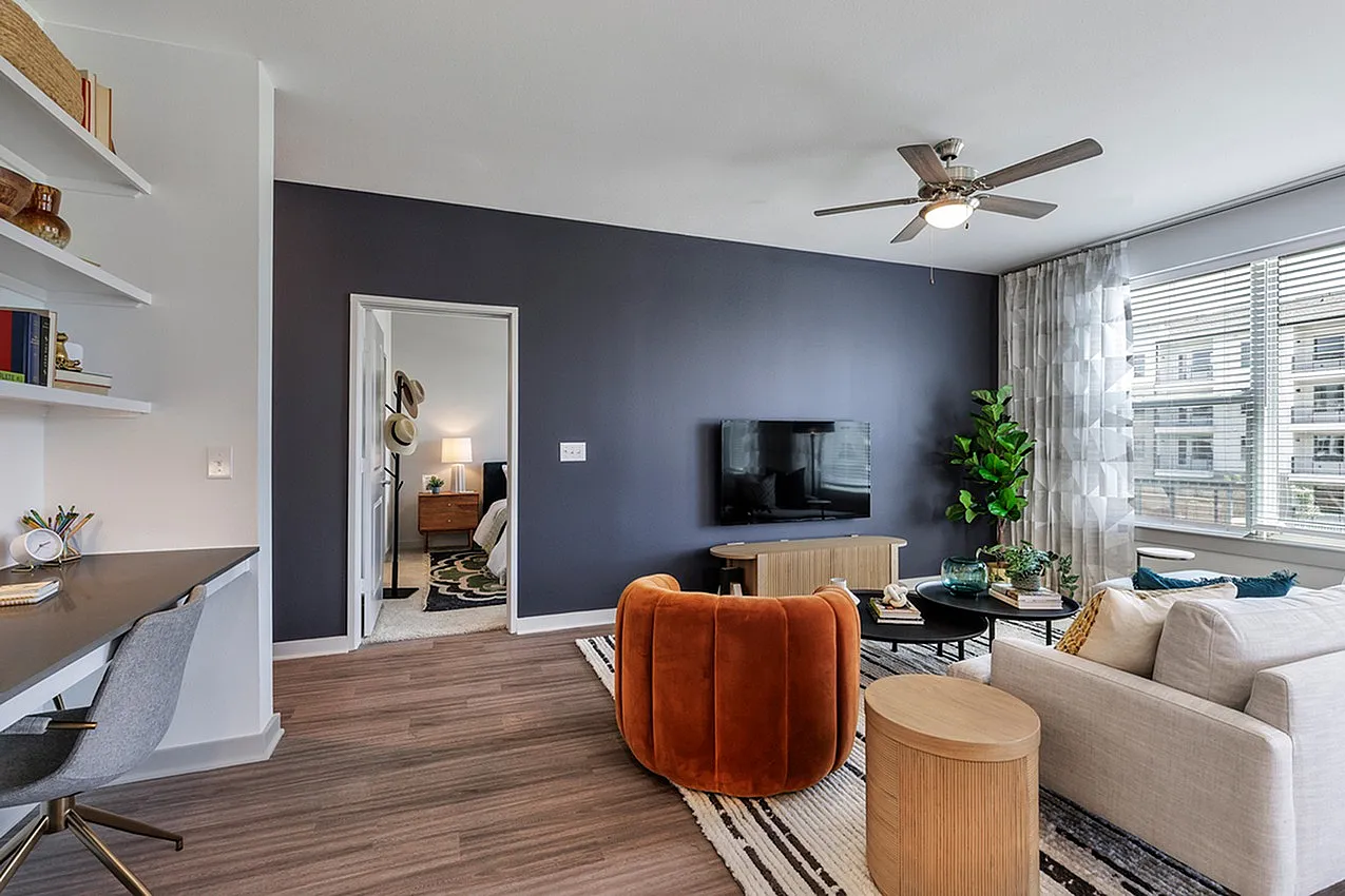 Stylish living room with modern decor, featuring a plush orange chair, cozy sofa, and a sleek entertainment setup.