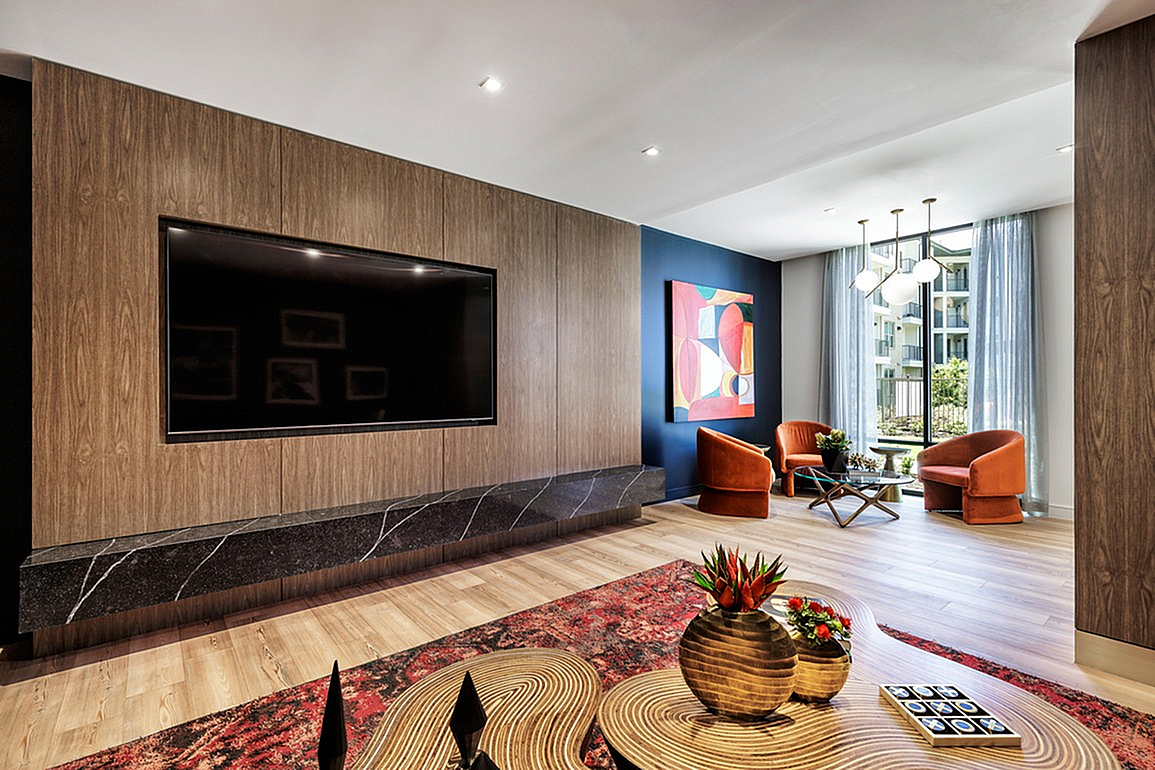 Chic modern living room with wood paneling, large TV, vibrant artwork, and elegant lighting.