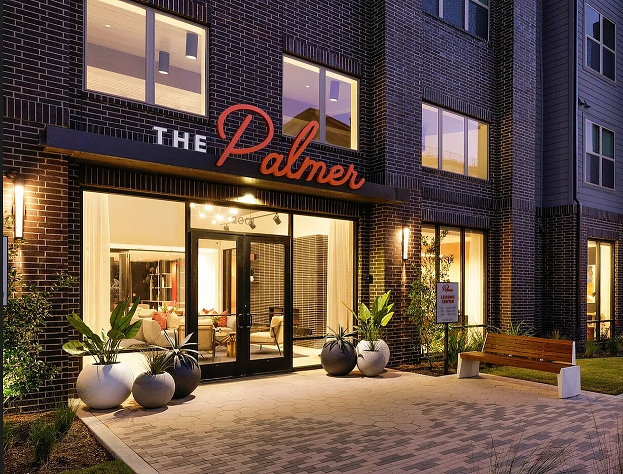 Elegant exterior view of The Palmer apartment complex, showcasing stylish brickwork and welcoming entrance.