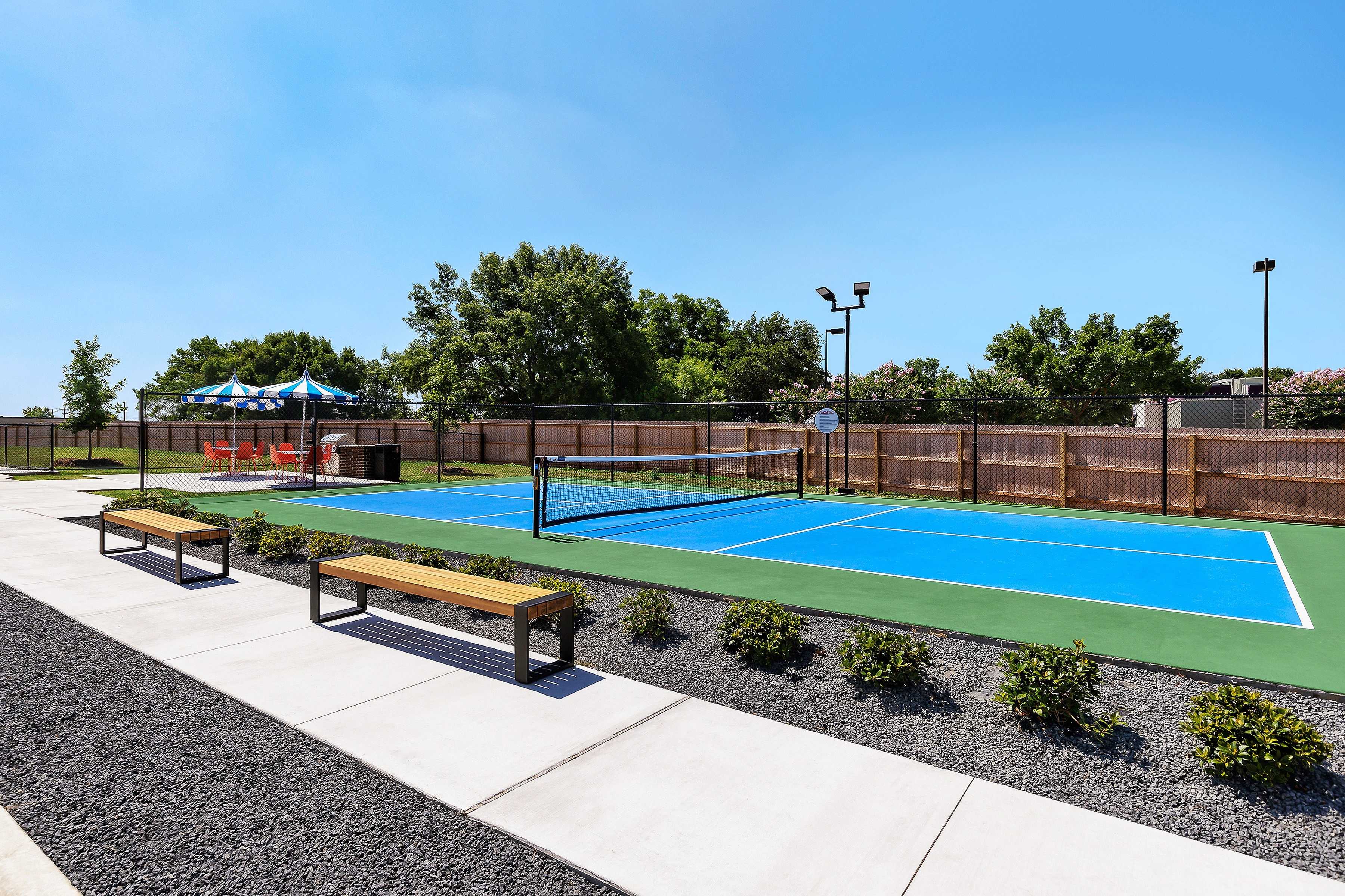 Beautifully maintained outdoor tennis court with benches and a scenic backdrop.