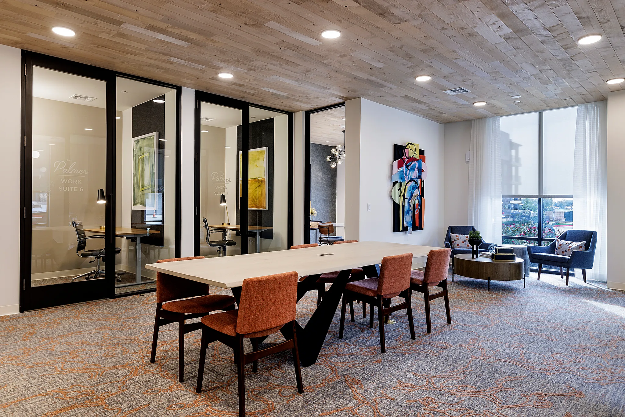 Contemporary office lounge with a long conference table, stylish chairs, and modern artwork.