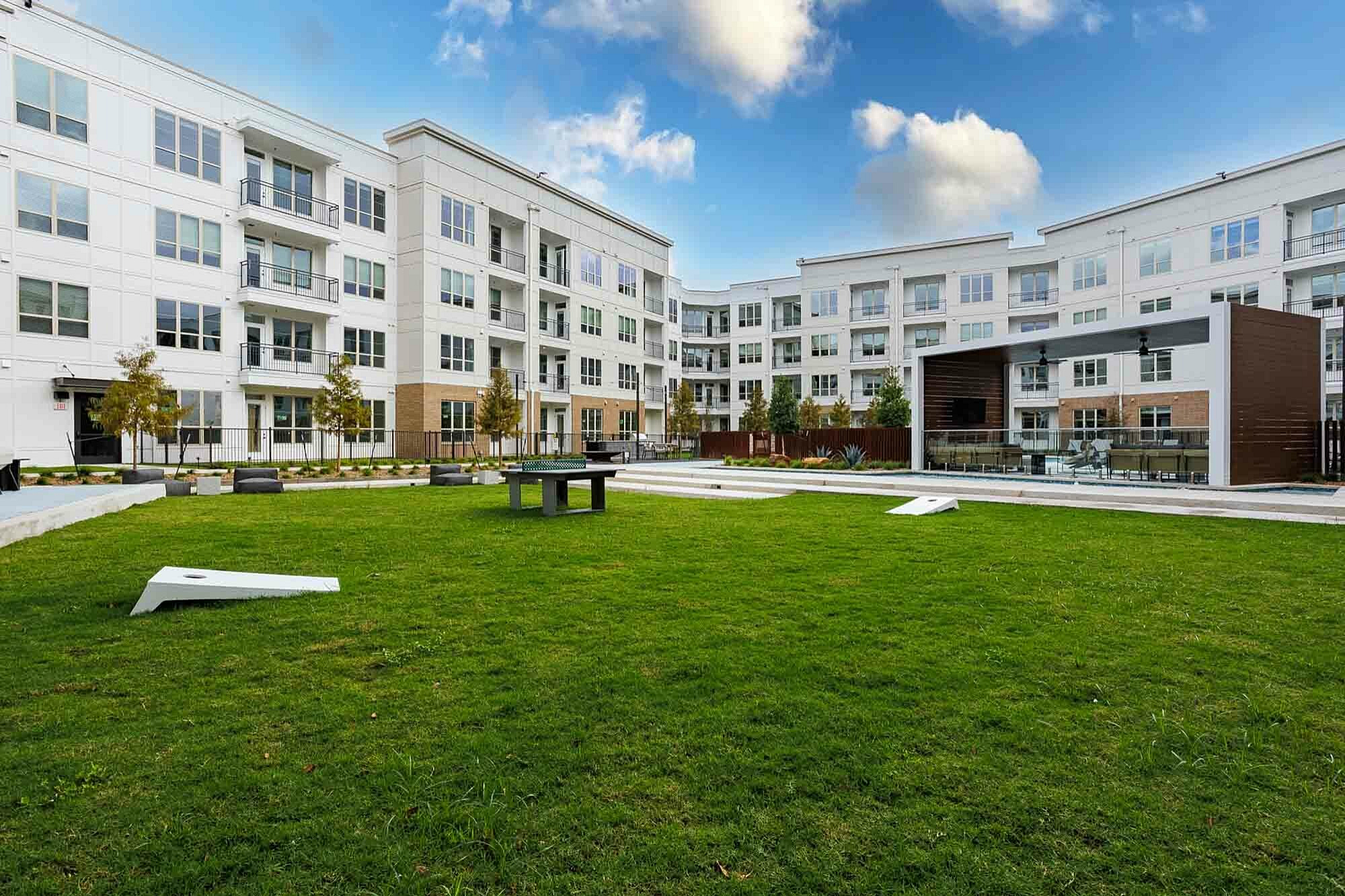 Modern apartment complex with a large, lush lawn and outdoor seating area | Caroline at Memorial | Houston, Texas