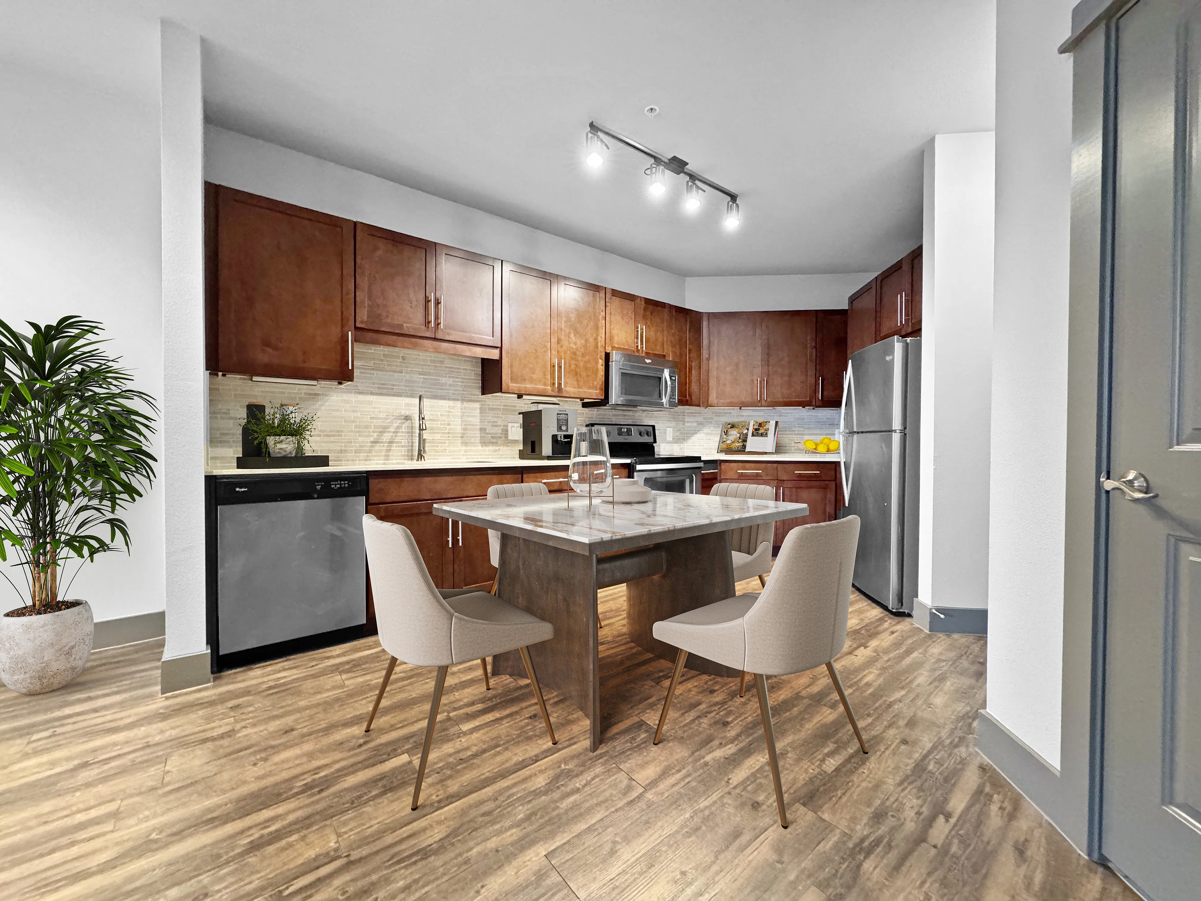 Modern kitchen with sleek stainless steel appliances, rich wooden cabinets, and a stylish dining area on elegant wooden flooring.