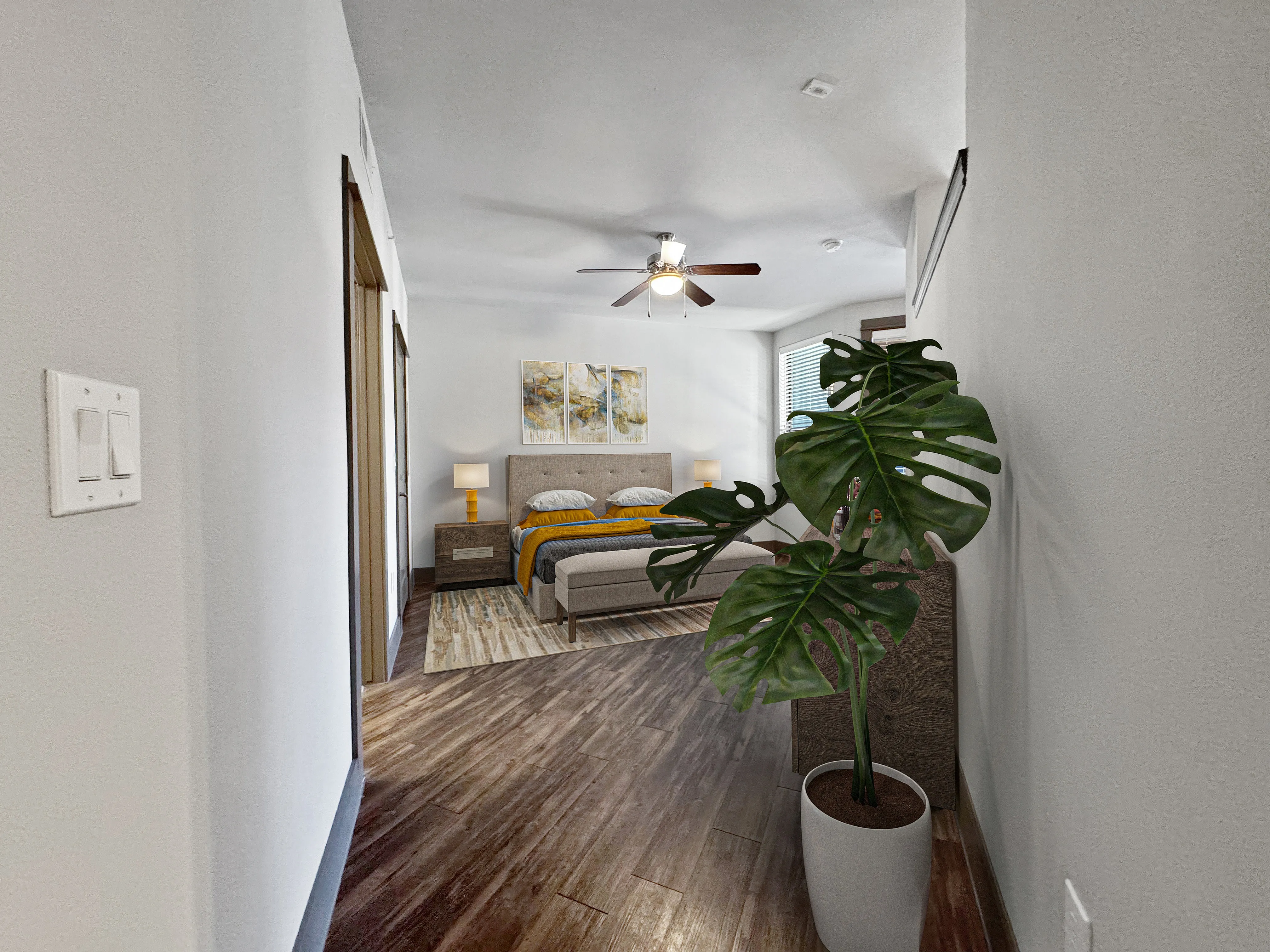 Inviting bedroom with modern decor, wooden flooring, and a potted plant adding a touch of nature.
