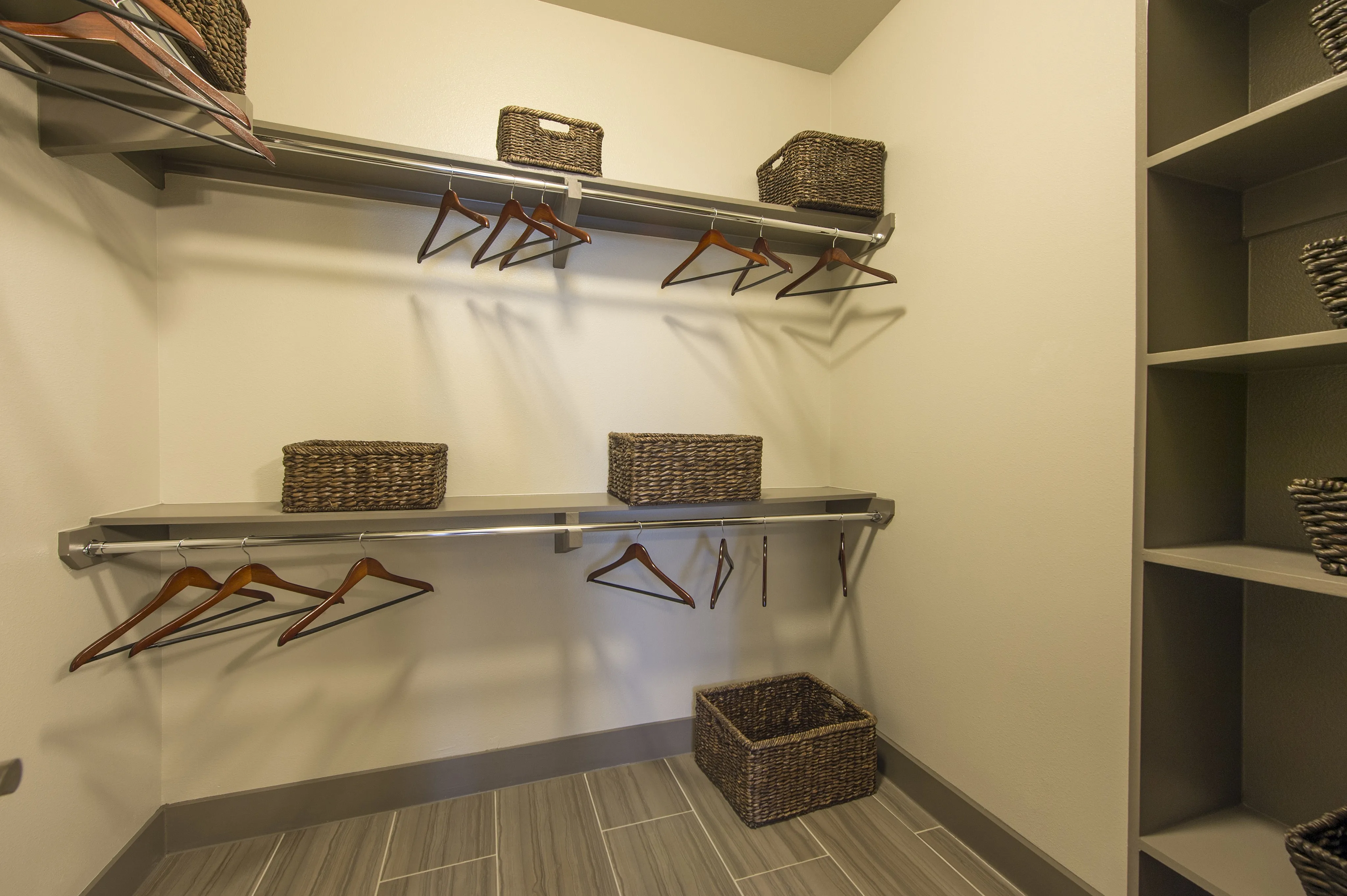 Spacious walk-in closet with elegant shelving, sleek accents, and stylish wicker storage baskets.