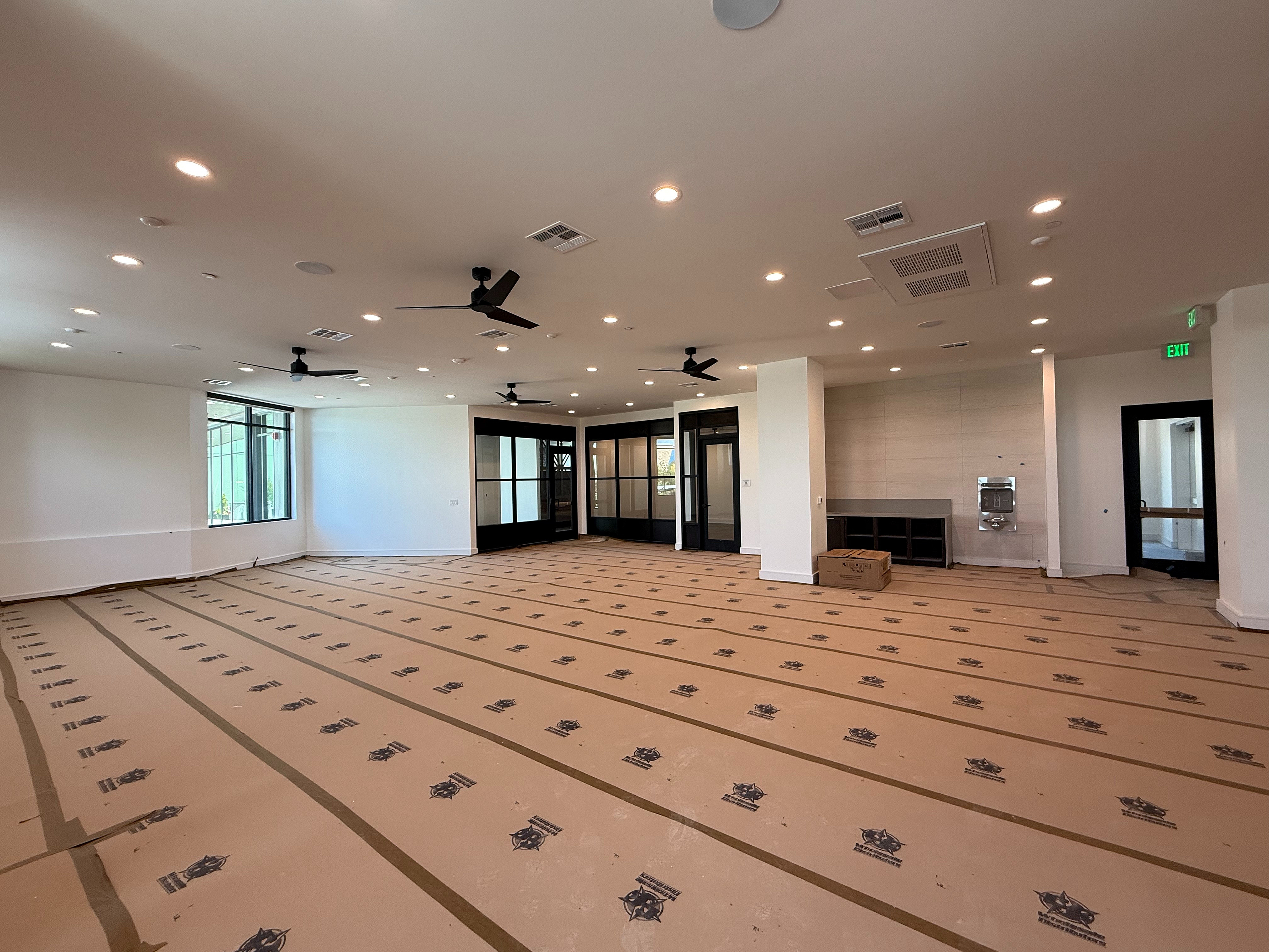 Spacious, modern interior with large windows, sleek ceiling fans, and abundant lighting, ideal for contemporary living or creative workspace.