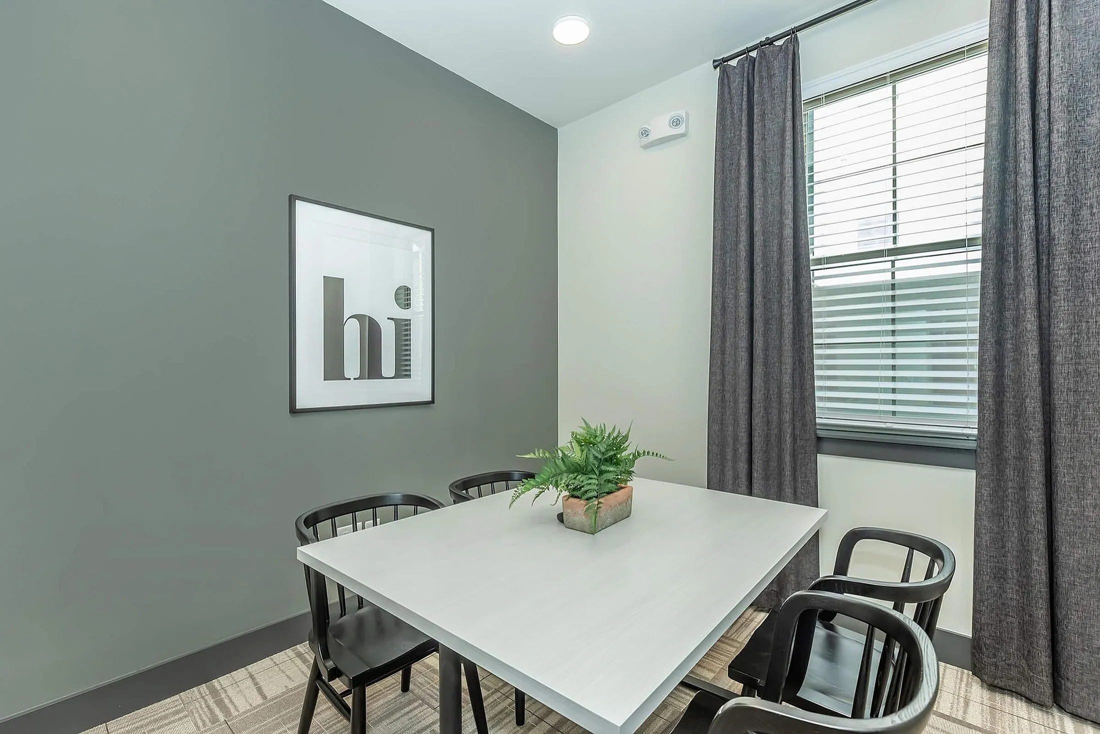 Modern dining area with stylish gray walls, elegant black chairs, and a chic framed artwork.