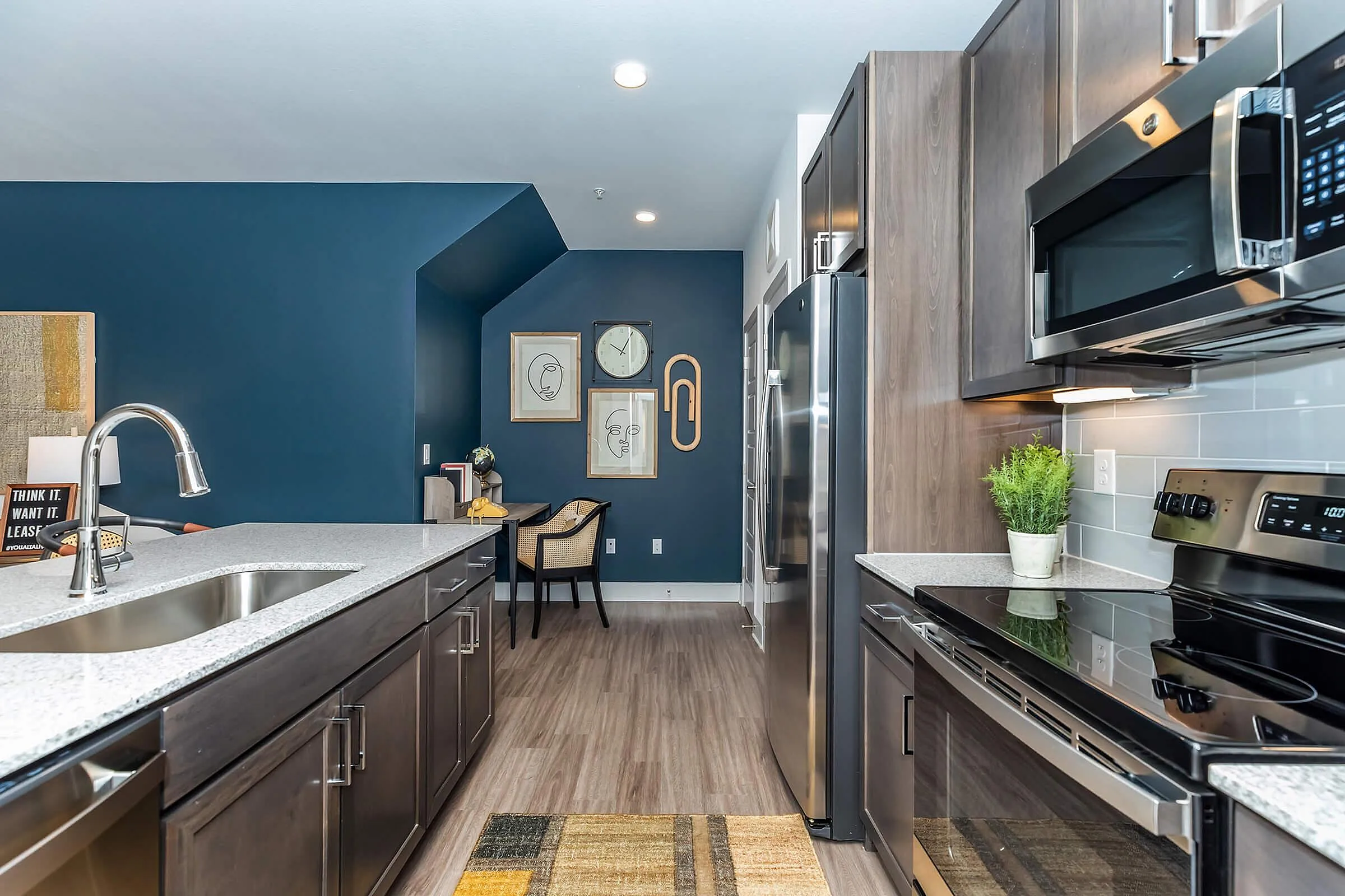 Modern kitchen with sleek stainless steel appliances, elegant blue accent wall, and stylish artwork, perfect for entertaining.