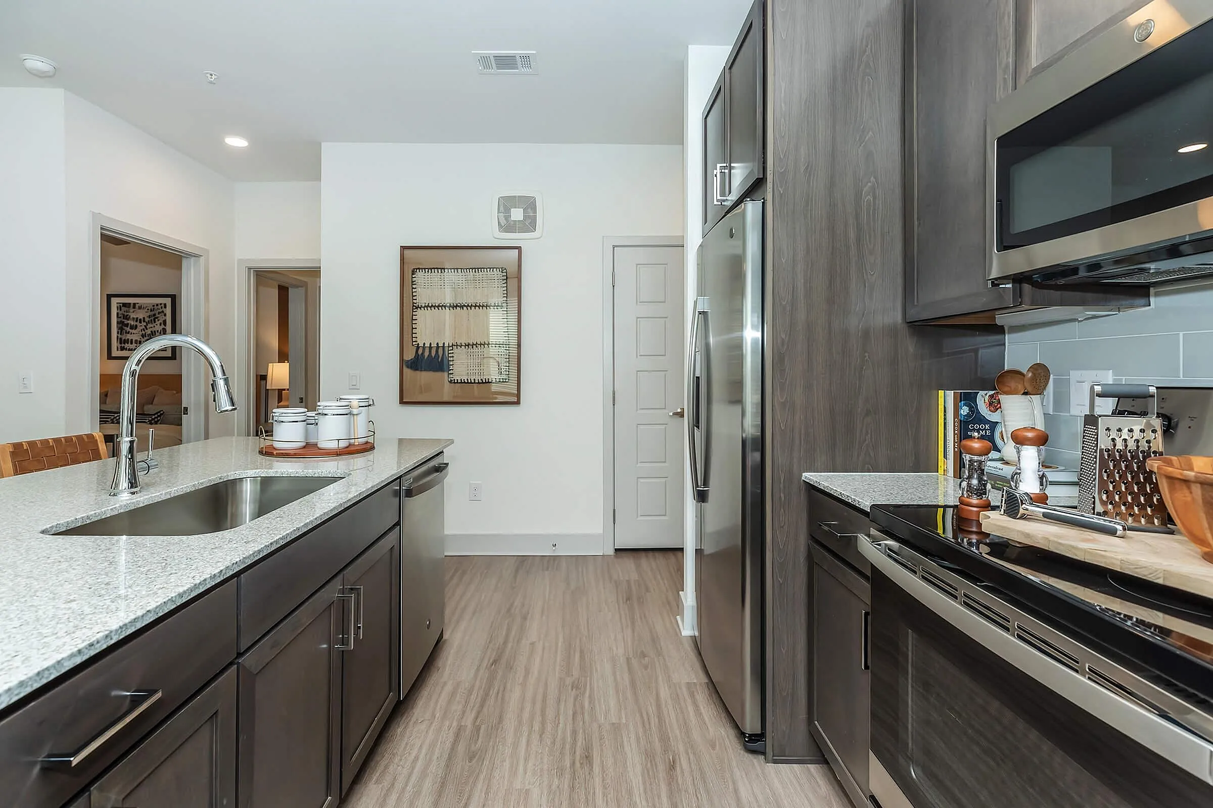 Modern kitchen with sleek dark wood cabinets, granite countertops, and stainless steel appliances, perfect for culinary enthusiasts.