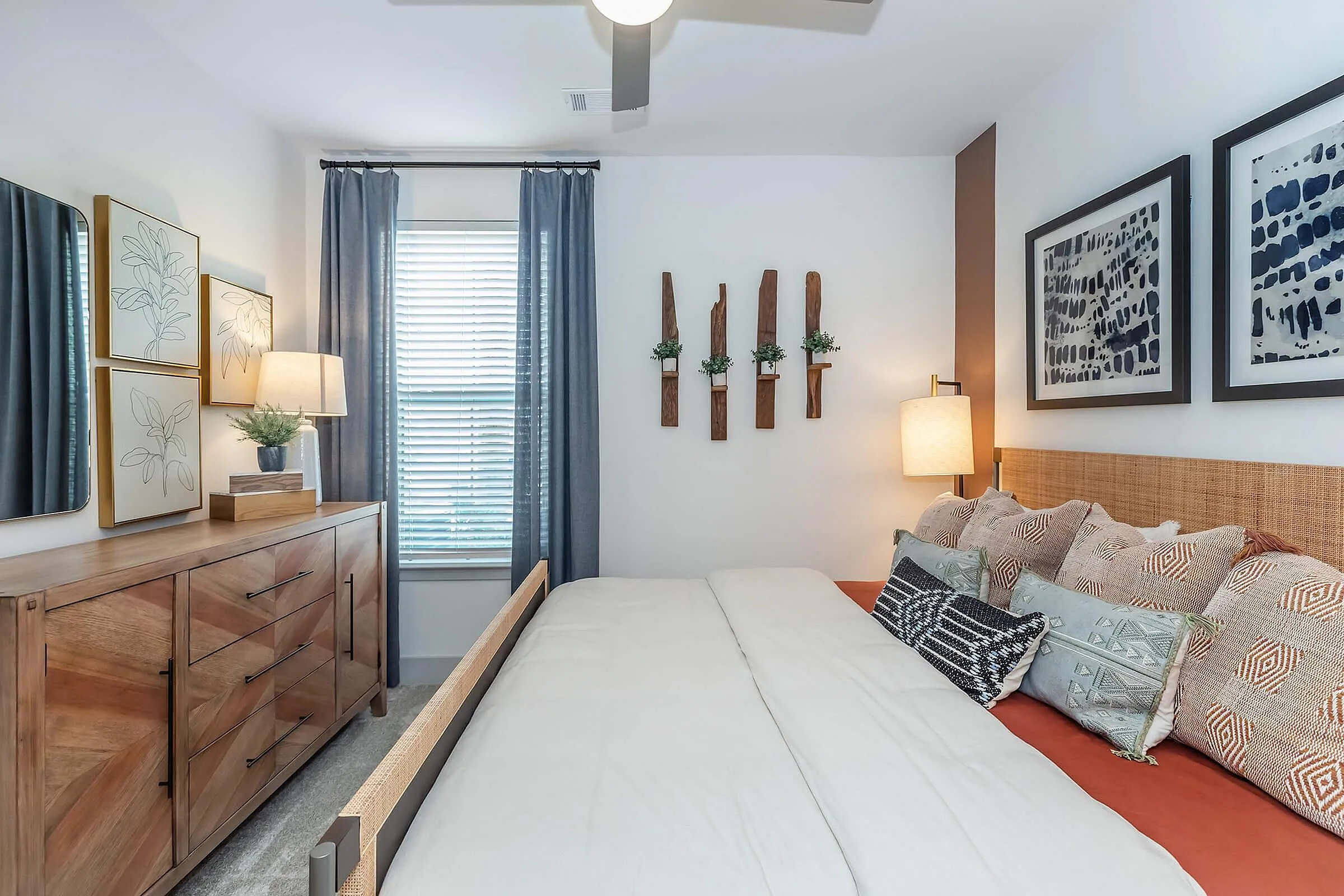 Inviting bedroom with elegant decor, featuring a cozy bed, stylish wooden dresser, and modern art enhancing a relaxing ambiance.