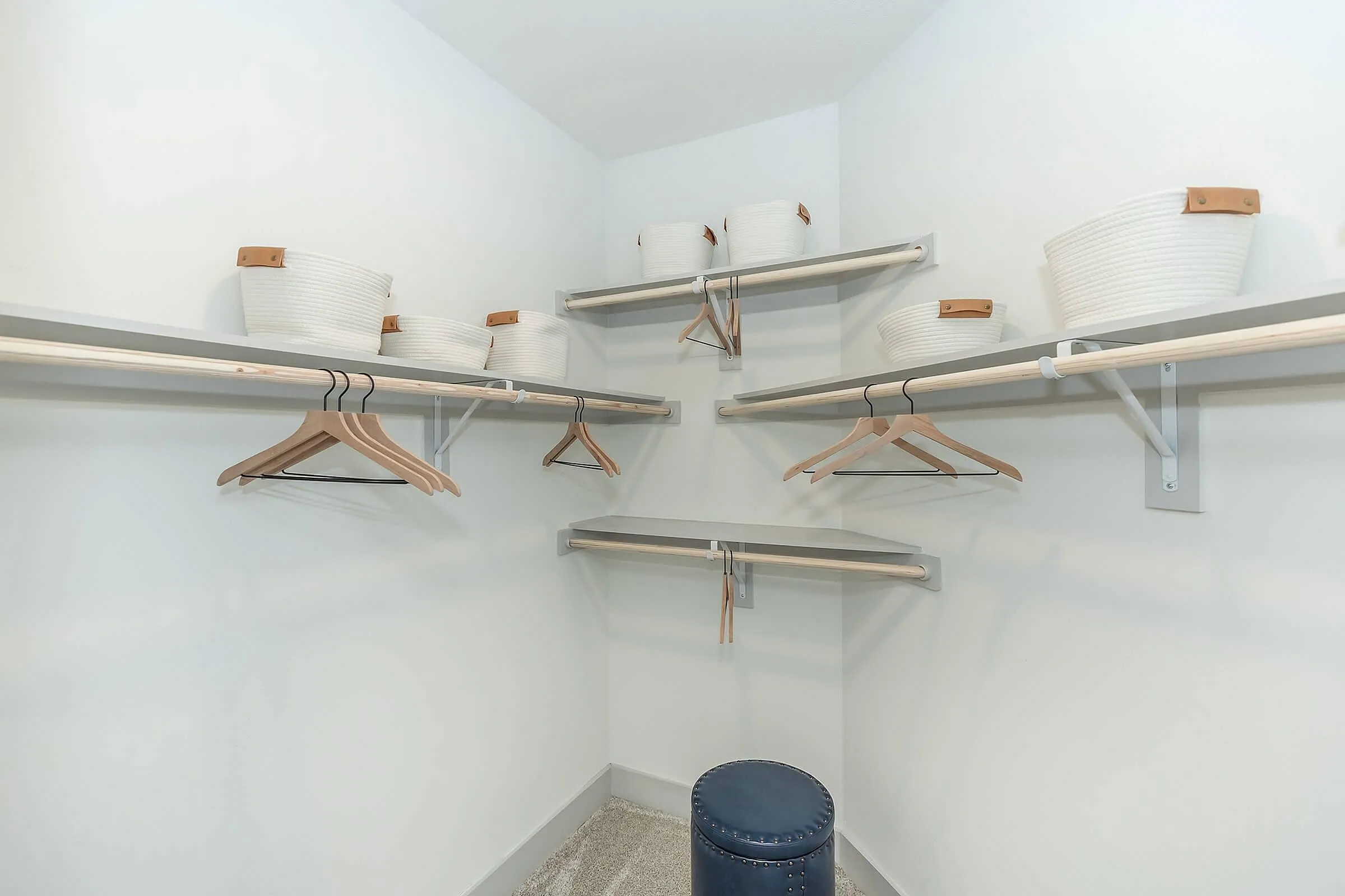 Spacious walk-in closet featuring modern shelving, elegant wooden hangers, and stylish white storage baskets.