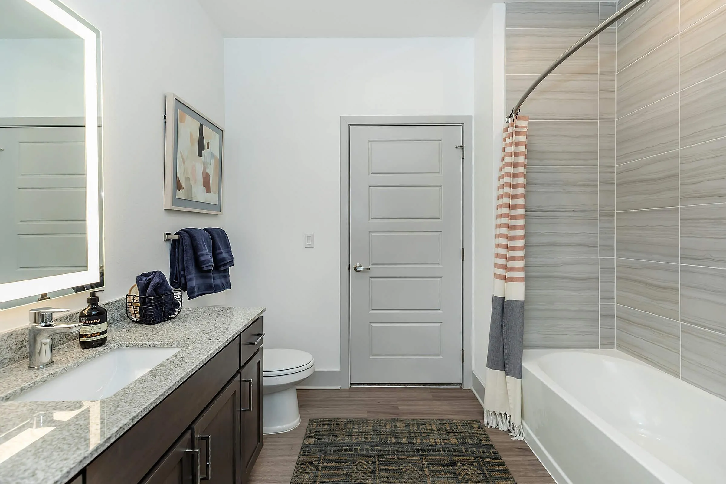 Elegant modern bathroom featuring a sleek granite countertop, stylish dark wood cabinets, and a cozy bathtub.