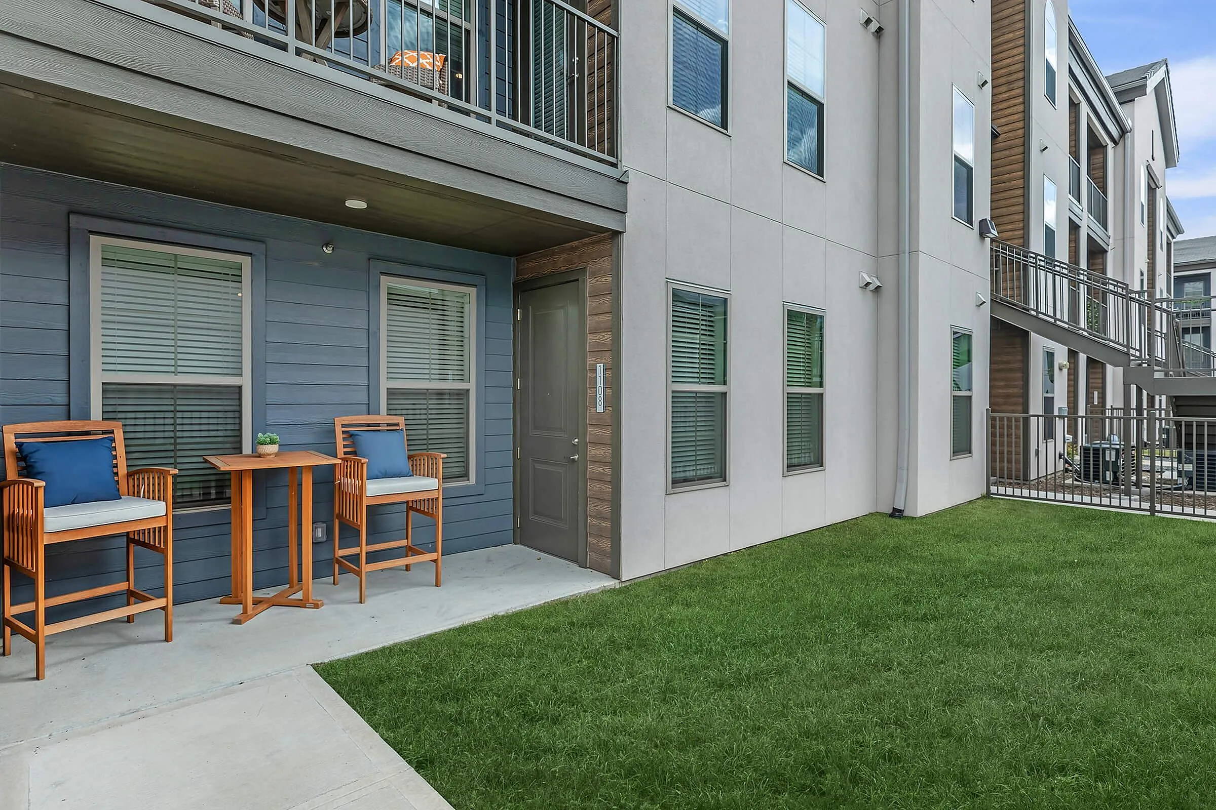 Charming apartment patio with stylish wooden seating and lush greenery, perfect for relaxation and outdoor enjoyment.