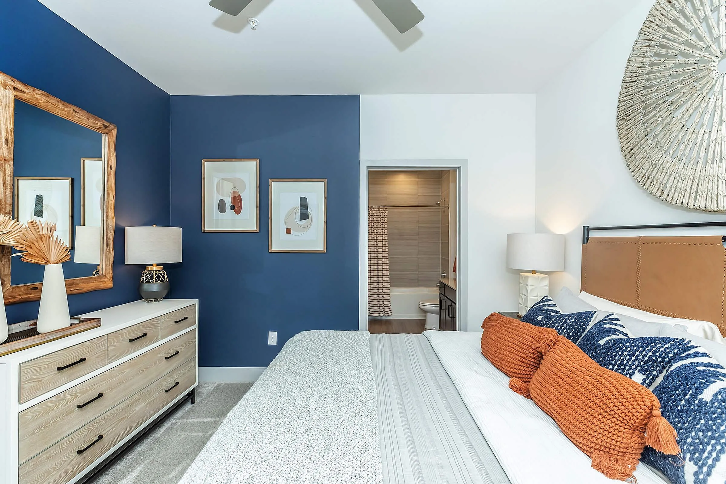 Chic bedroom with vibrant blue accent wall, modern decor, and en-suite bathroom, perfect for cozy relaxation.