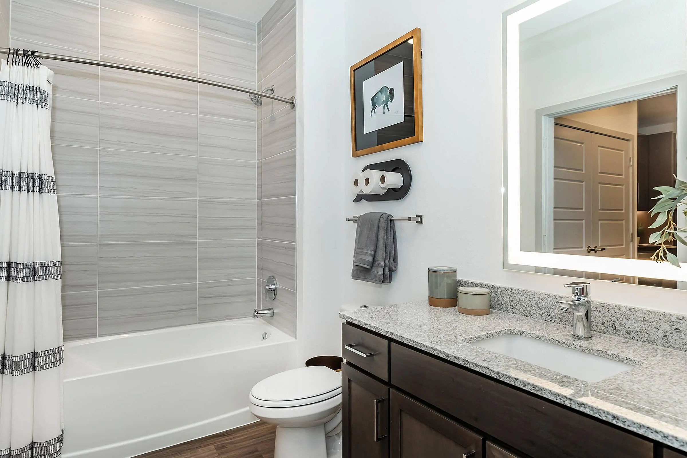Elegant modern bathroom with sleek gray tiles, a stylish vanity, and an illuminated mirror, offering a luxurious spa-like experience.