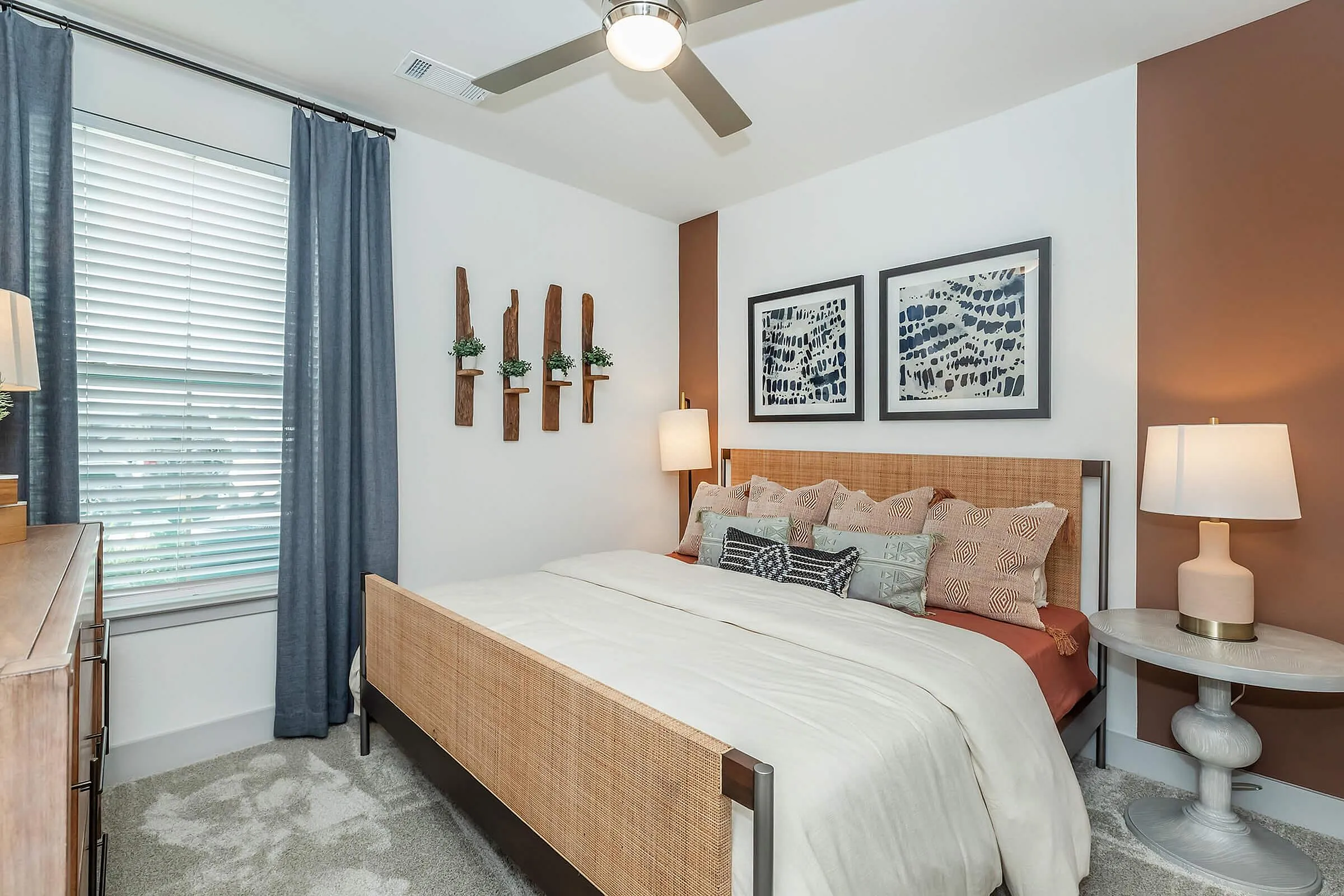 Charming bedroom with stylish decor, featuring a cozy bed with patterned pillows, modern art, and ambient lighting.