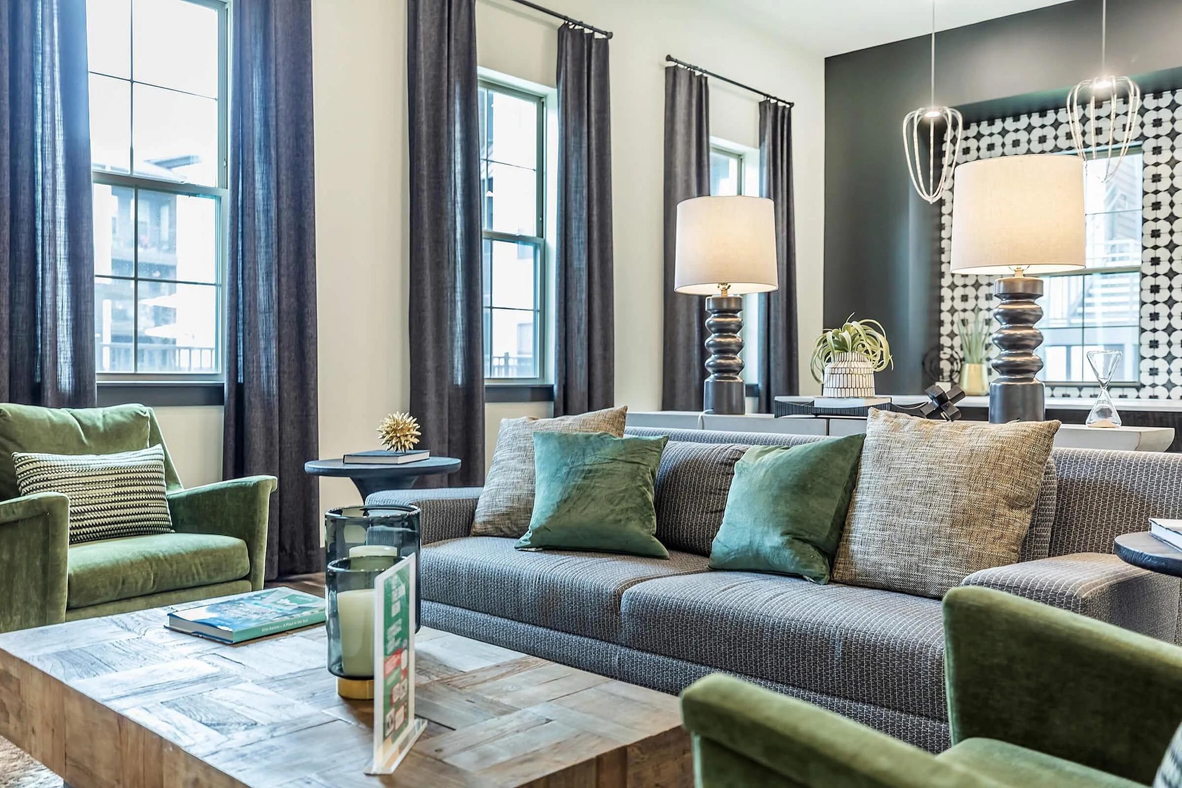 Elegant modern living room with stylish gray sofa, plush green armchairs, and cozy lighting, creating a warm and inviting atmosphere.