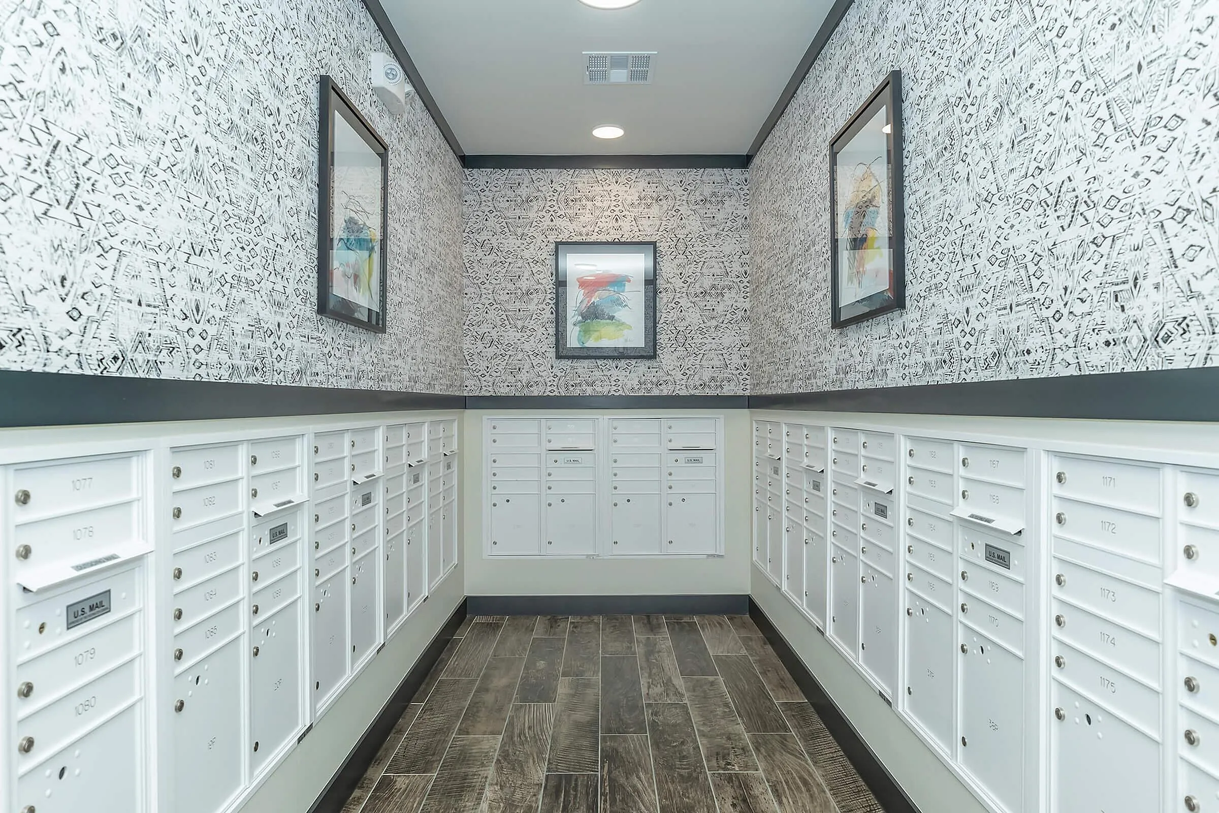Bright mailroom with elegant patterned walls, secure mailboxes, and modern artwork creating a stylish ambiance.