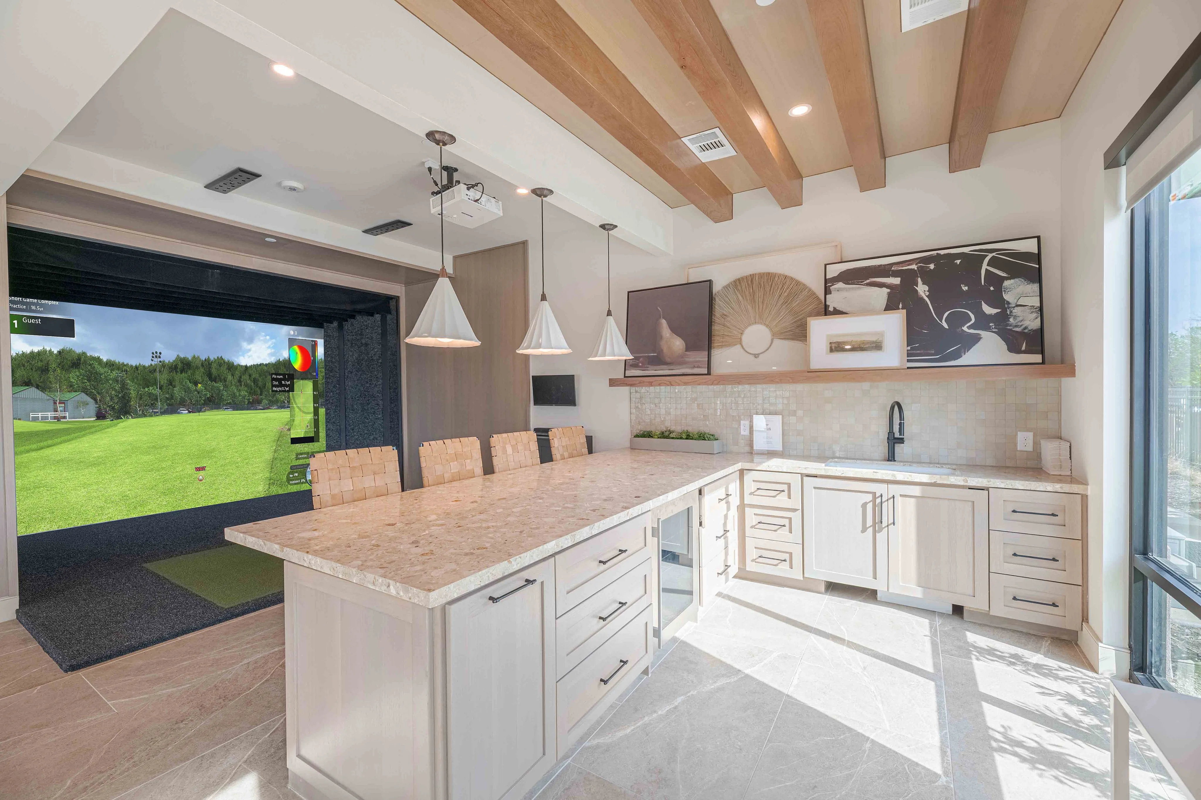 Luxurious modern kitchen with elegant marble countertops, stylish pendant lighting, and an integrated virtual golf simulator in the open-plan design.