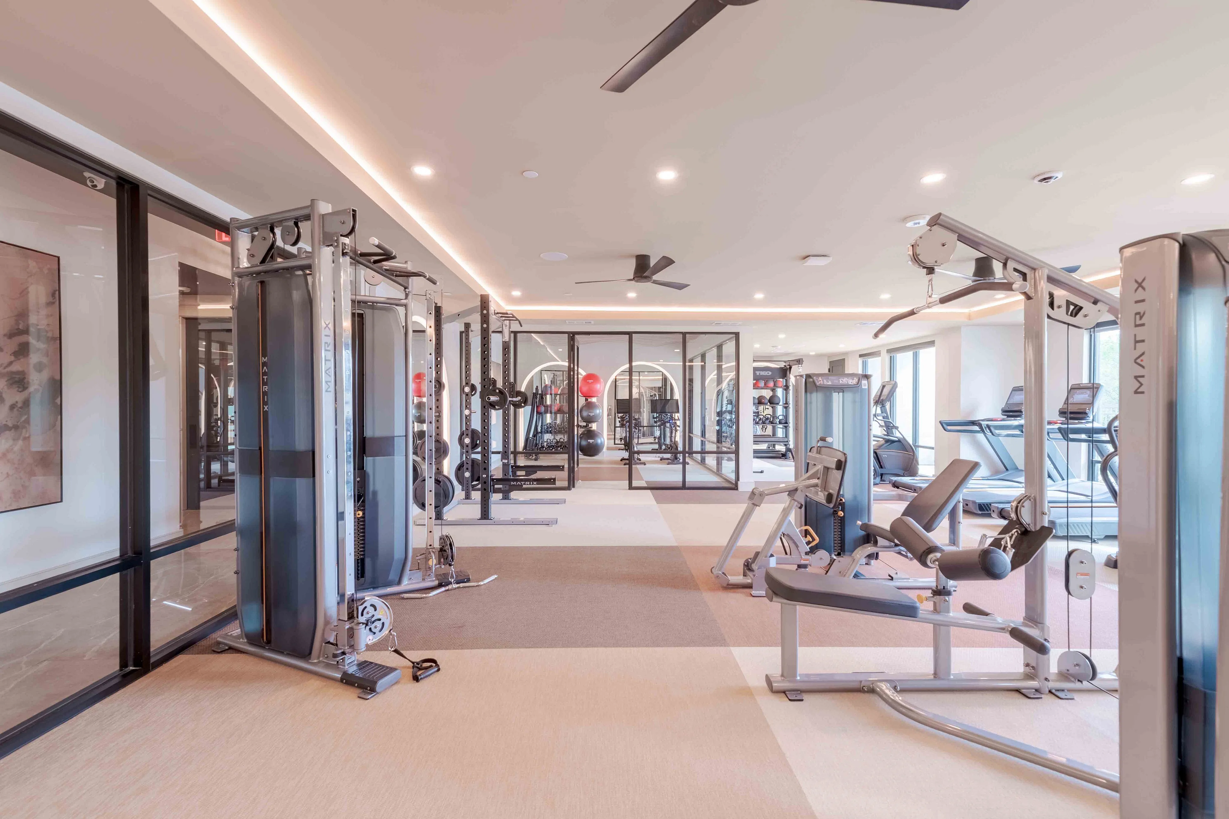 Modern fitness center with state-of-the-art gym equipment, sleek design, and large windows for natural light.