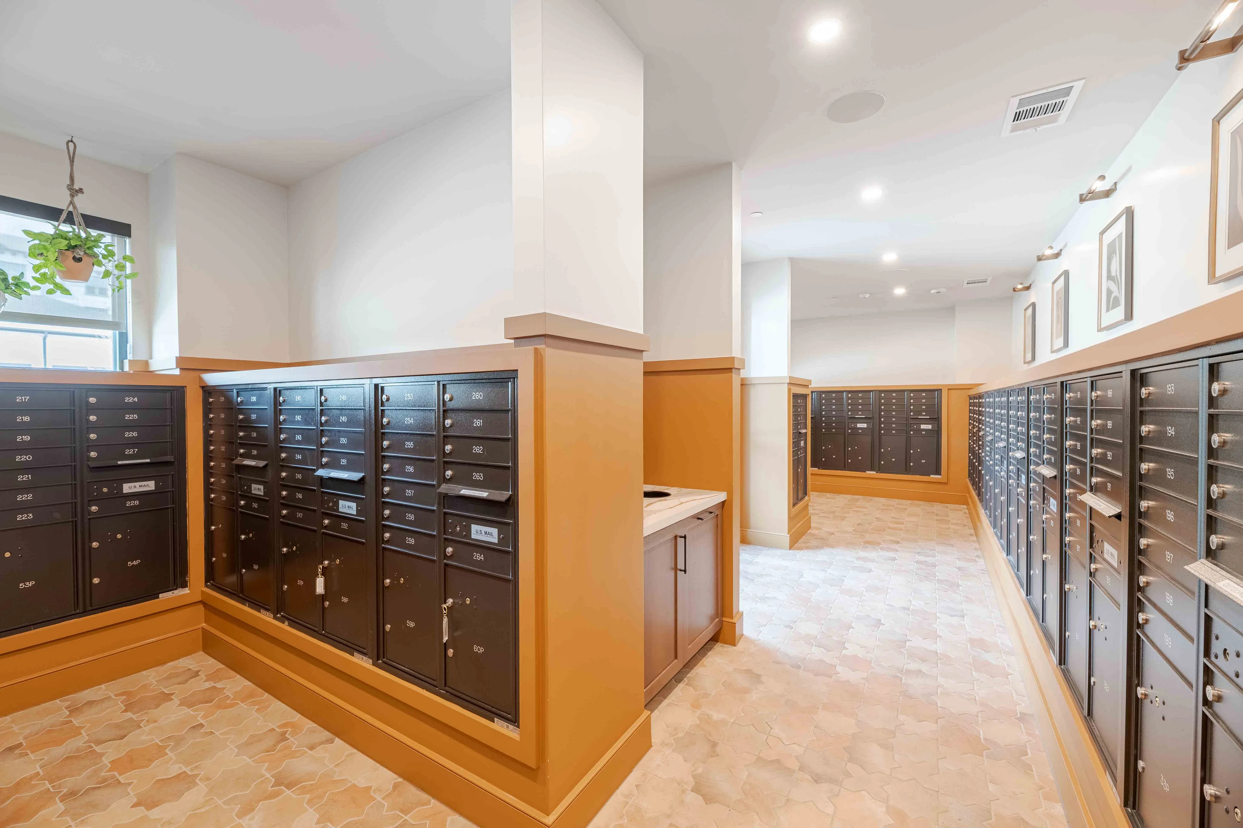 Bright apartment mailroom with organized mailboxes, elegant tile flooring, and chic decor.