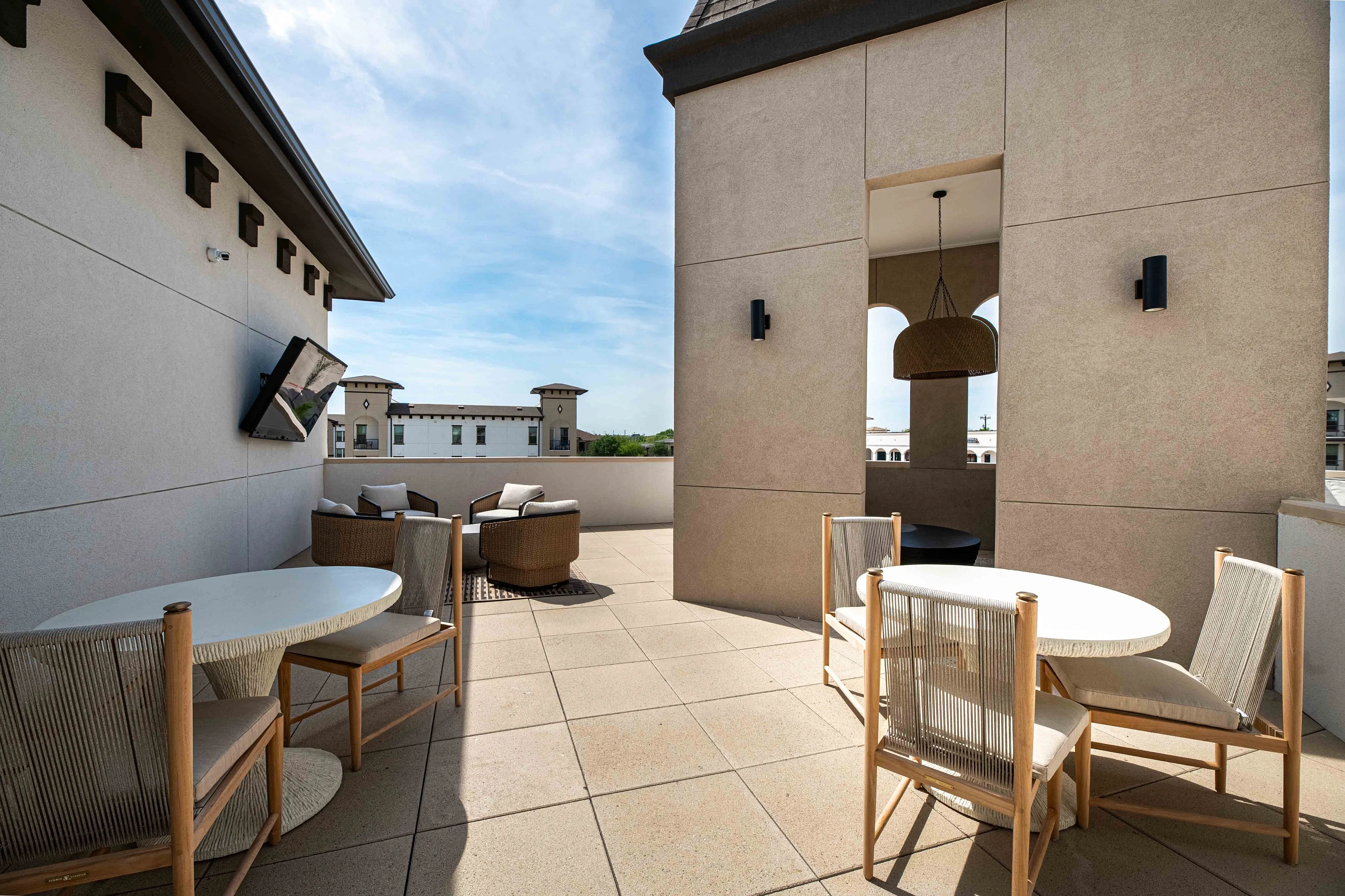 Luxurious rooftop terrace featuring stylish seating areas, modern architecture, and scenic views under a bright blue sky.