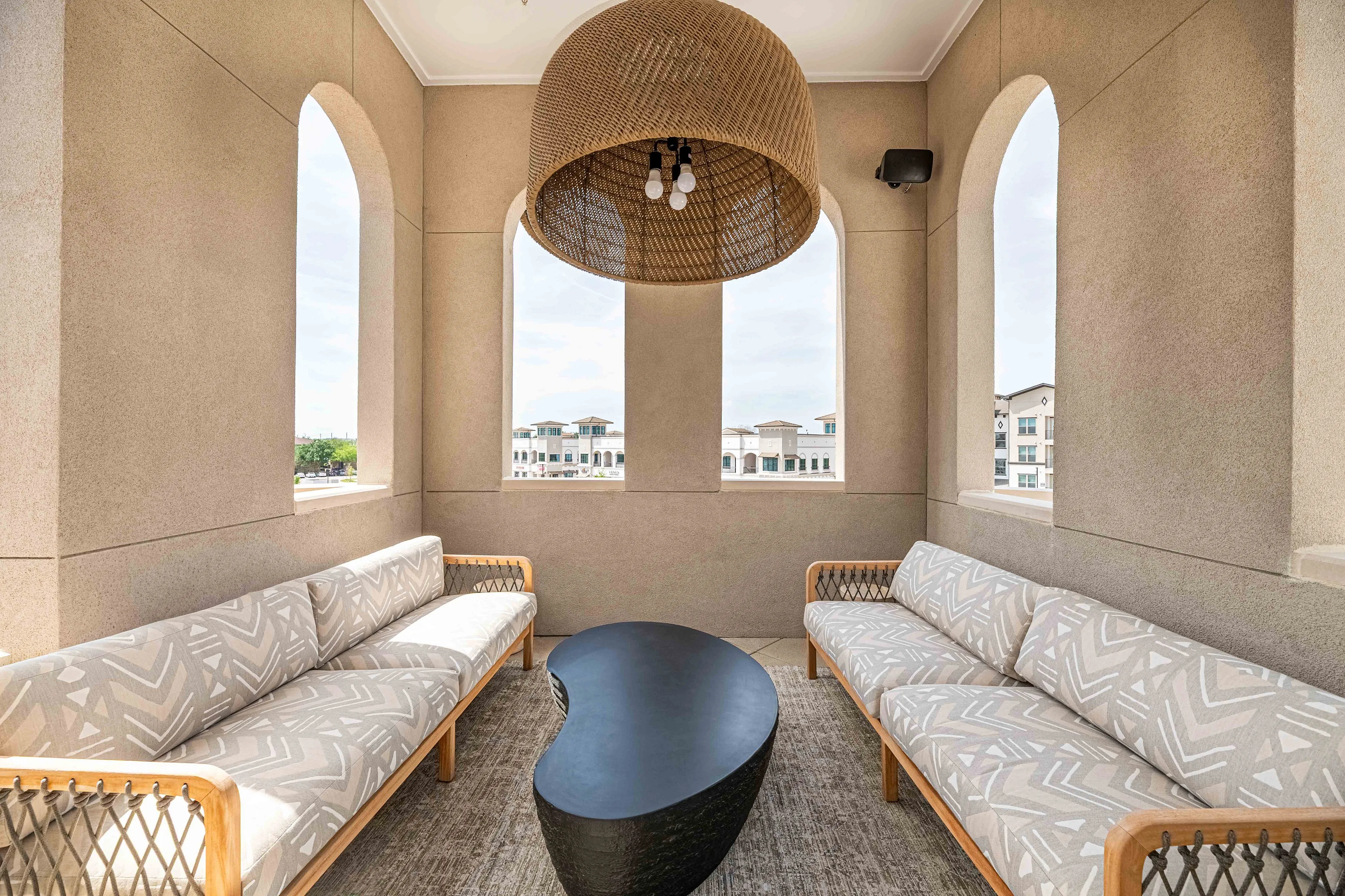 Chic balcony with elegant arched windows, cozy seating, and a modern coffee table, offering a picturesque view of the surrounding architecture.