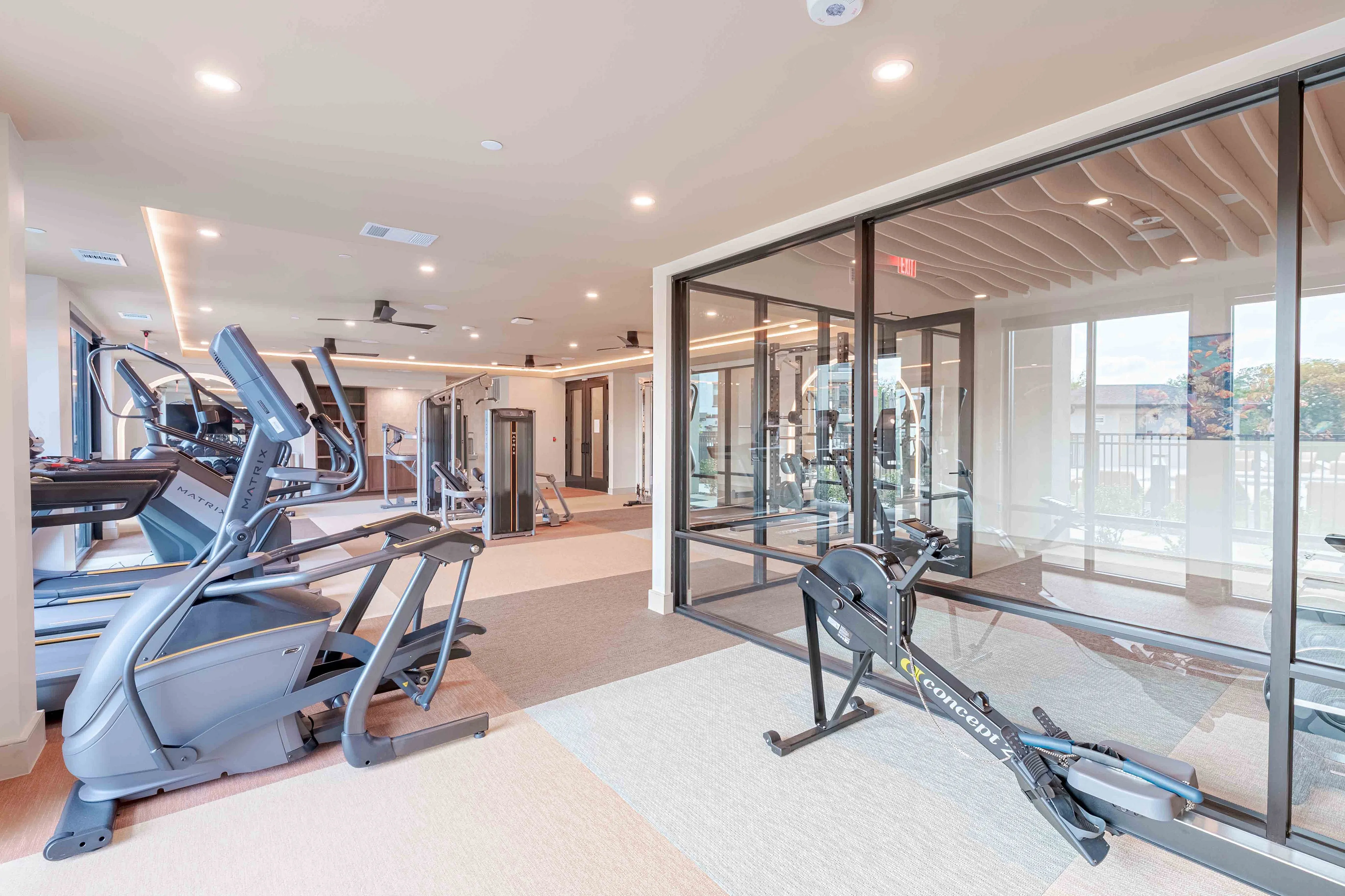 Modern fitness center with state-of-the-art equipment, including treadmills, weight machines, and a rowing machine, illuminated by sleek overhead lighting.