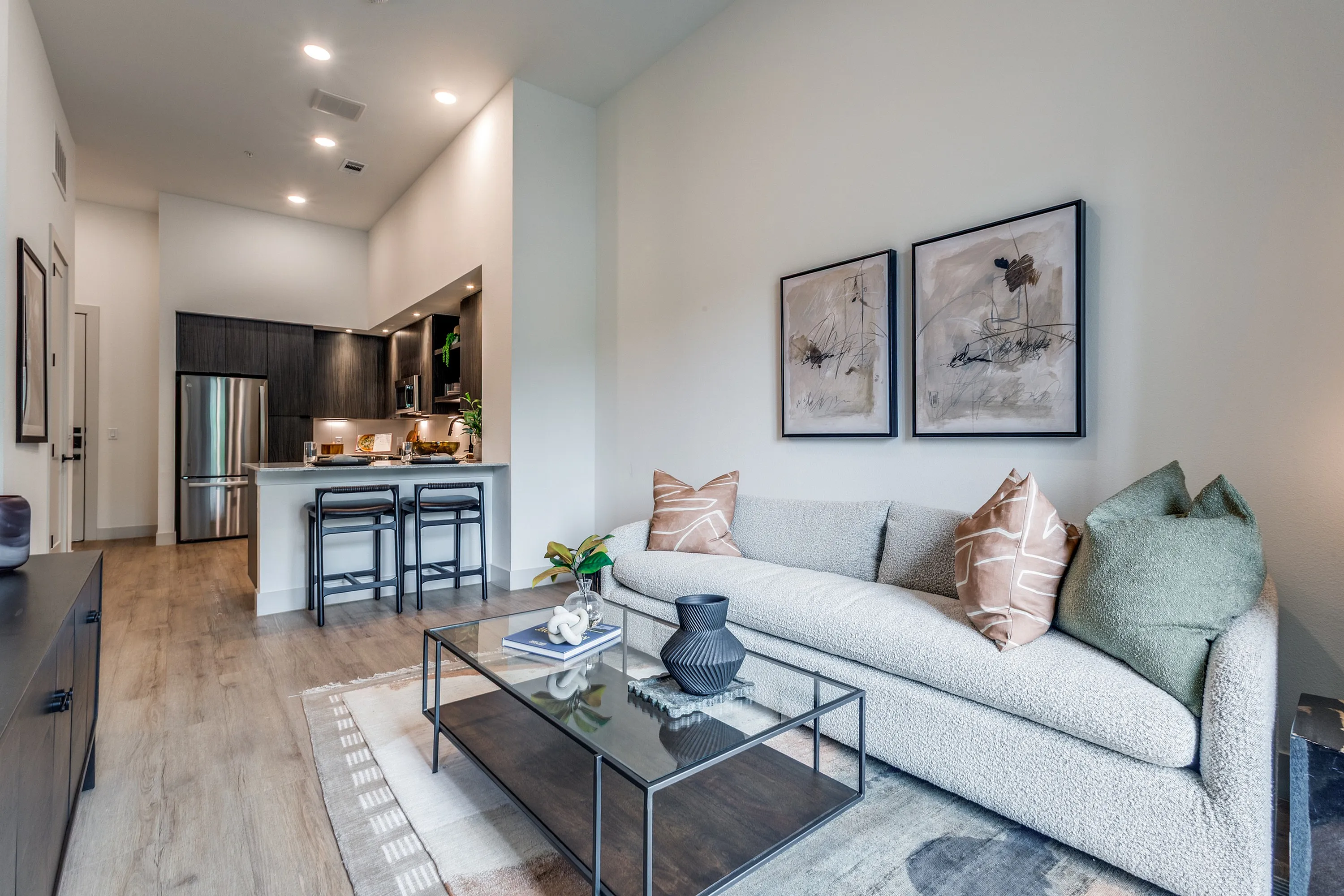 Elegant open-concept living space with sleek modern kitchen, cozy sofa, and stylish decor, perfect for relaxing and entertaining.