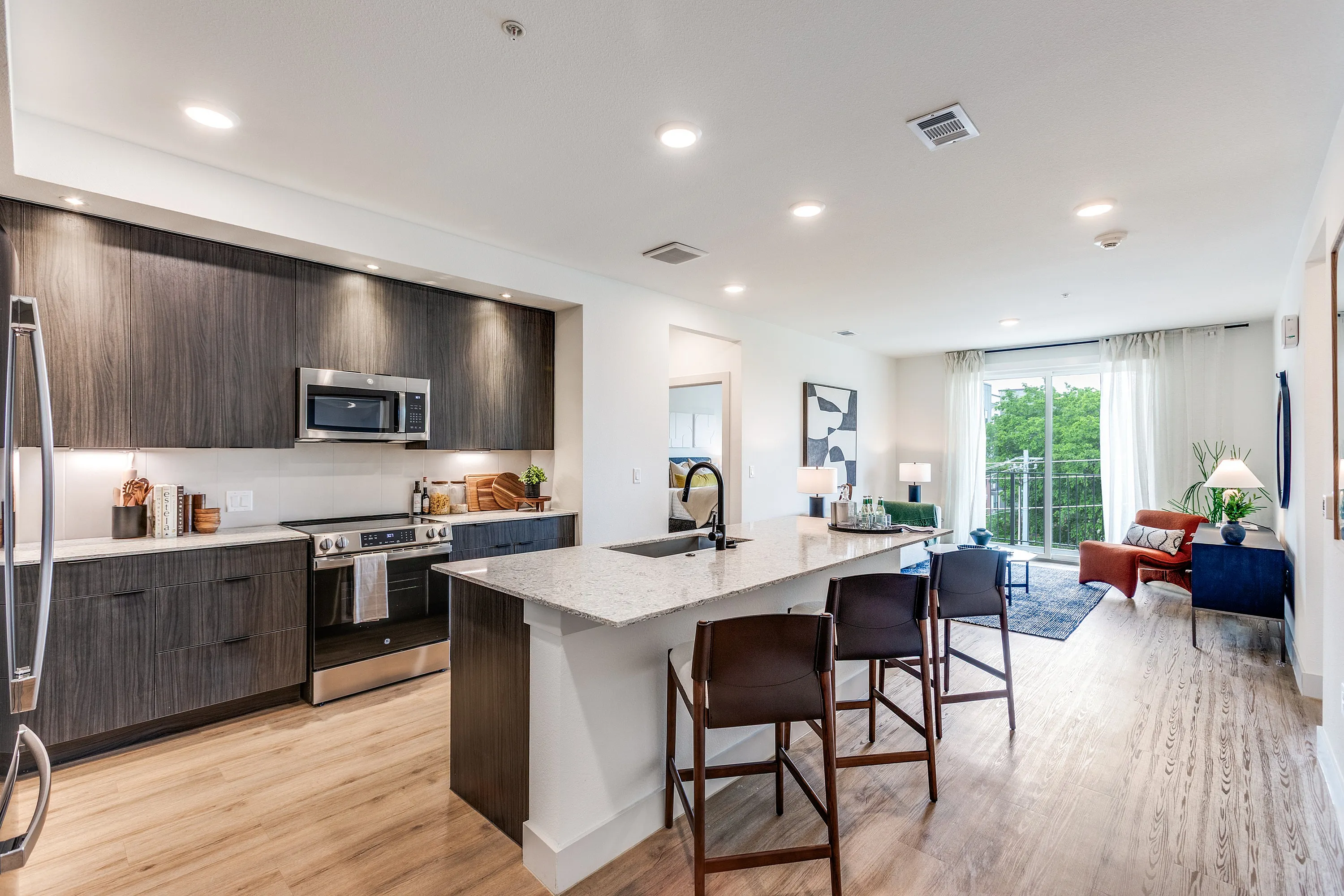 Luxurious open-concept kitchen and living room with sleek modern design, featuring a spacious island, stylish seating, and abundant natural light.