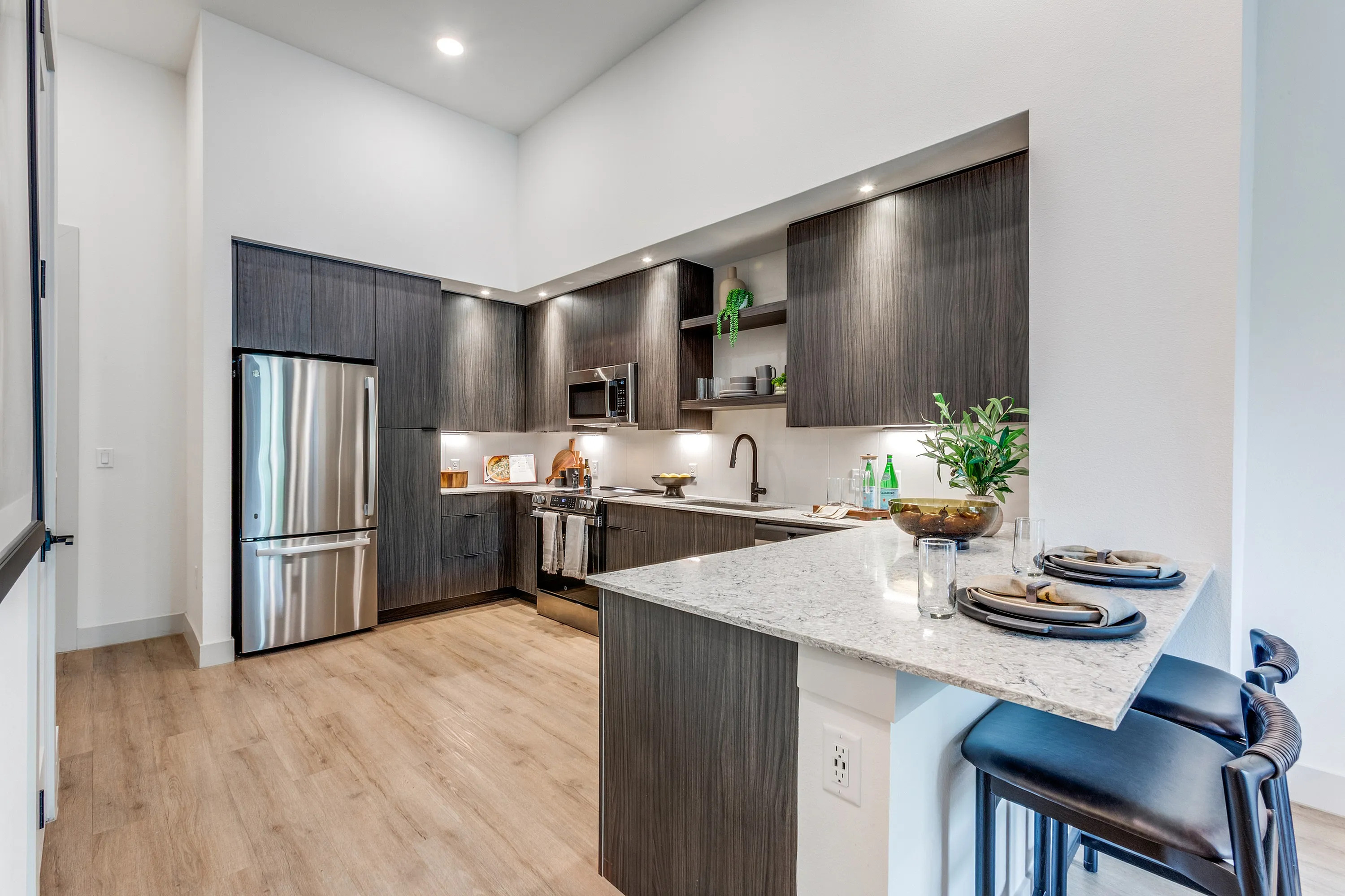 Modern kitchen with sleek dark wood cabinetry, stainless steel appliances, and chic breakfast bar seating.