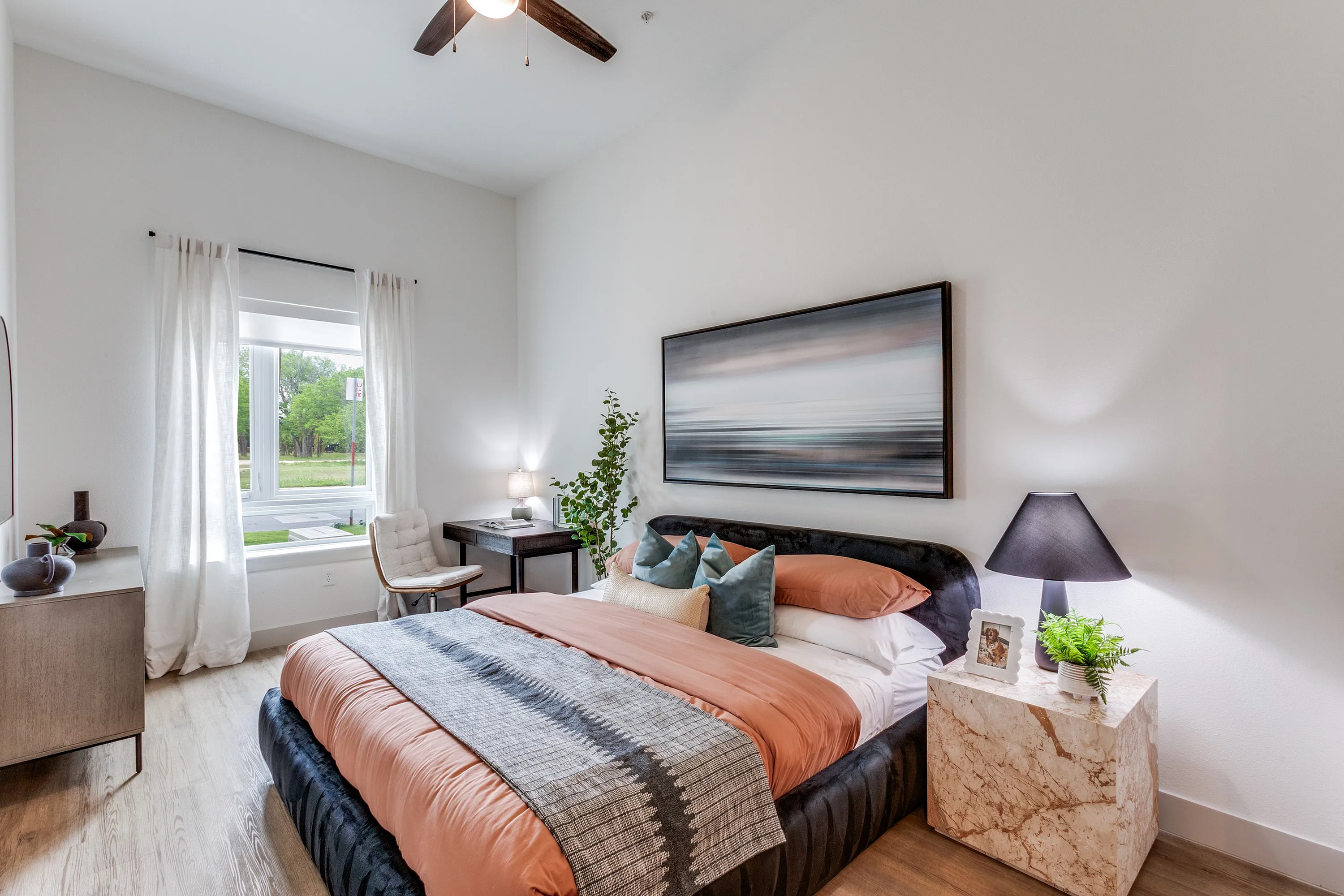 Cozy bedroom with elegant decor featuring a plush bed, stylish art, and a bright window view.
