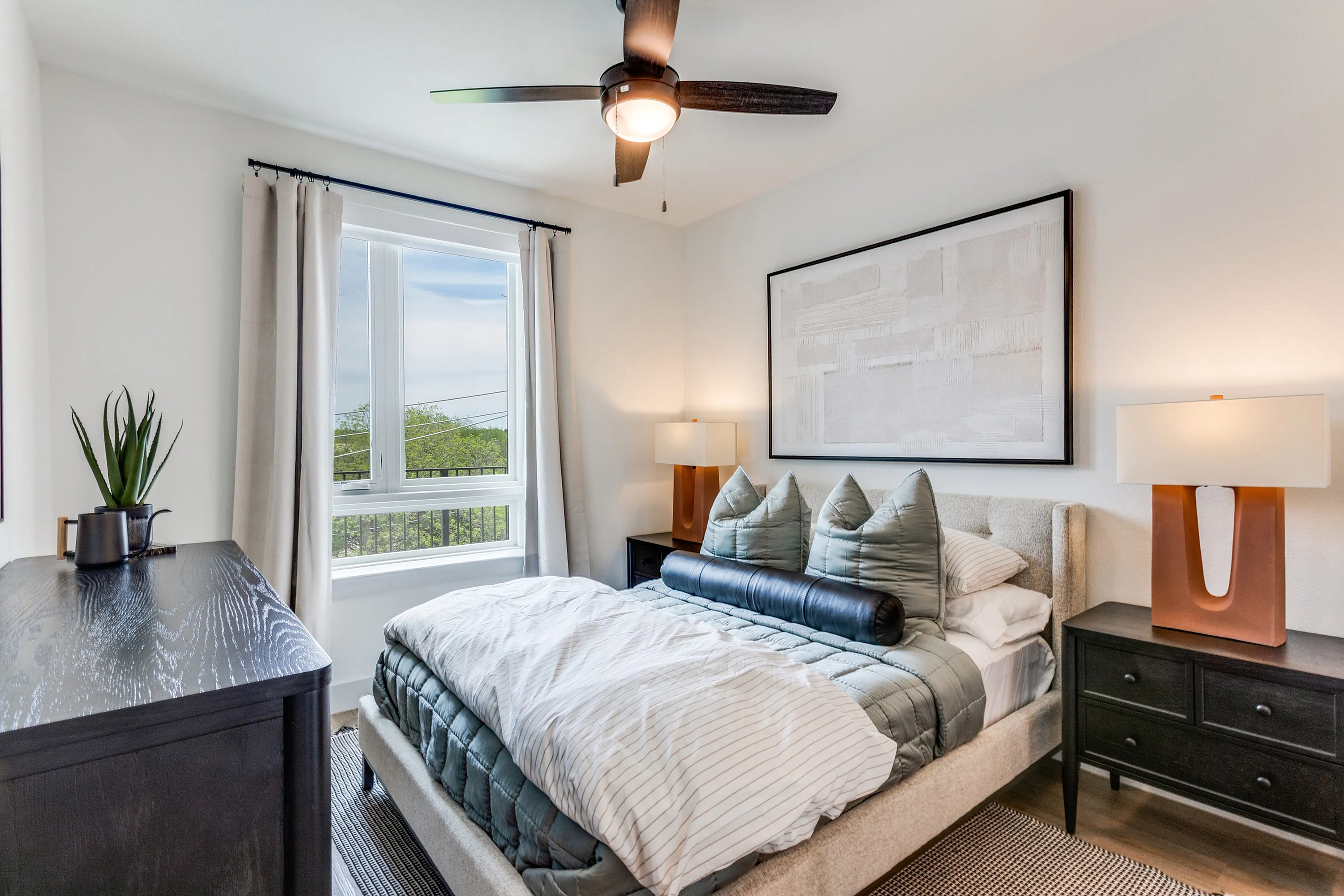 Bright and cozy bedroom with modern decor, featuring a plush bed, stylish lamps, and a large window offering scenic views.