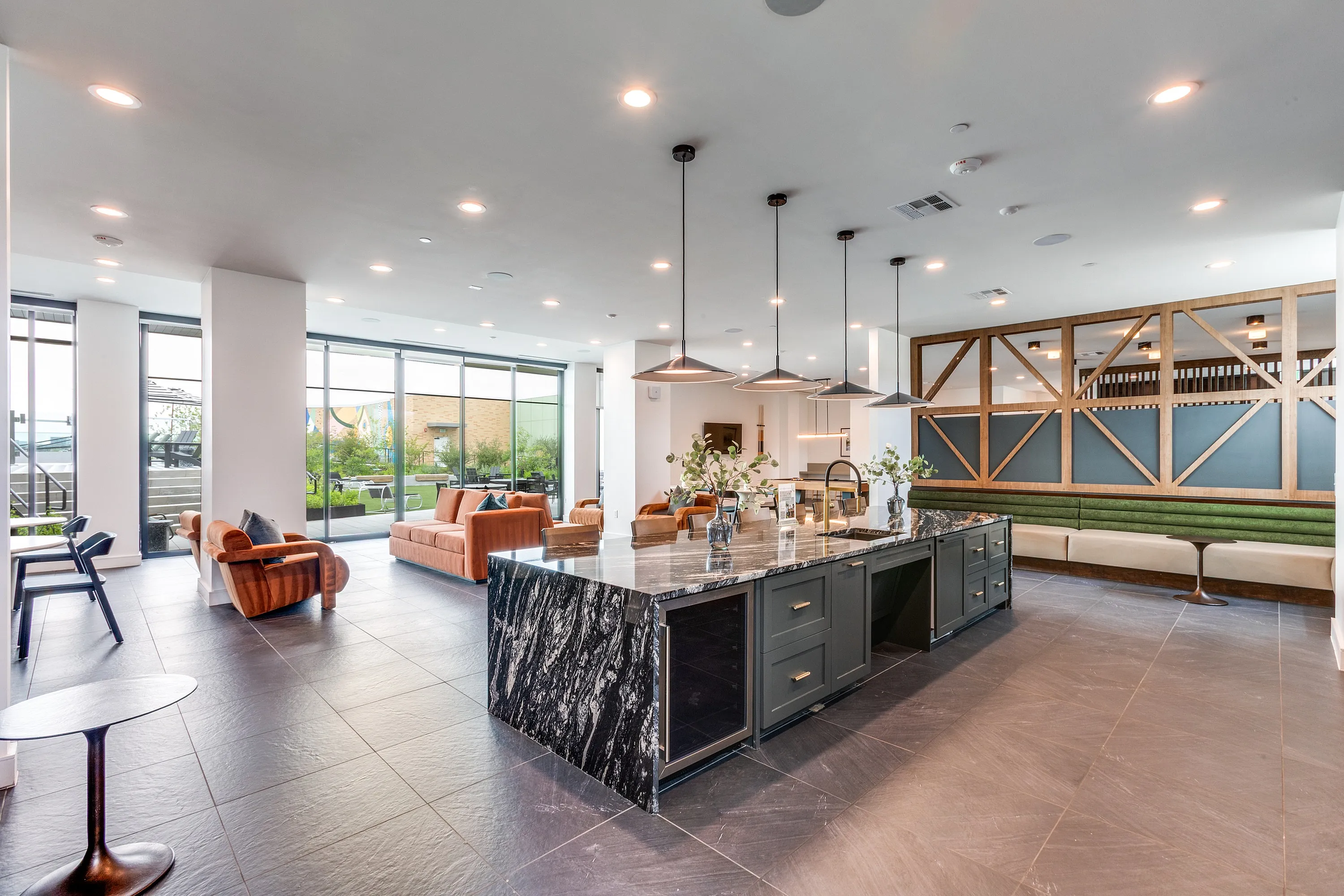Luxurious open-concept living space featuring modern kitchen island, elegant seating, and floor-to-ceiling windows with scenic views.
