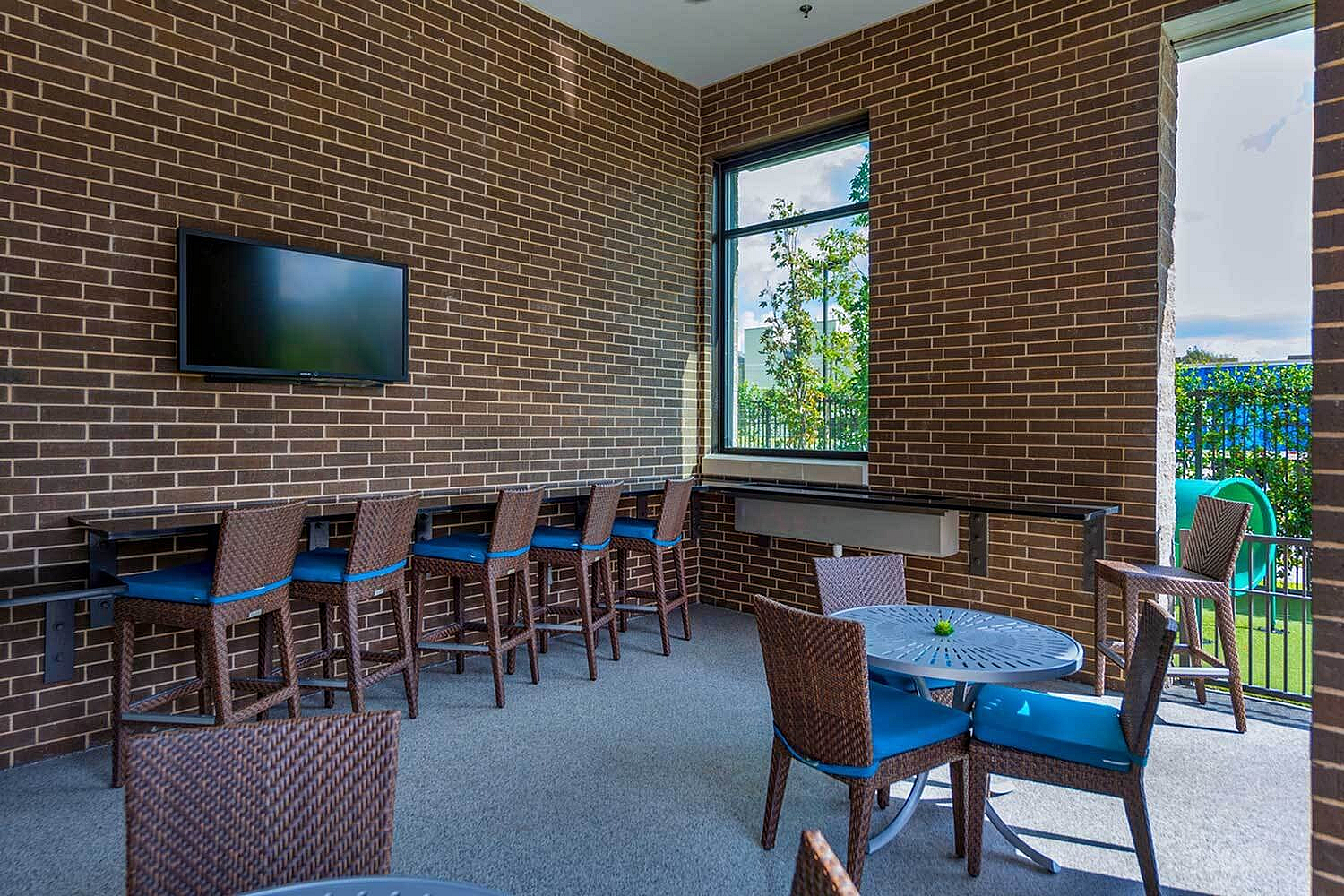 Inviting communal space with modern wicker seating, large flat-screen TV, and vibrant outdoor views, perfect for social gatherings.