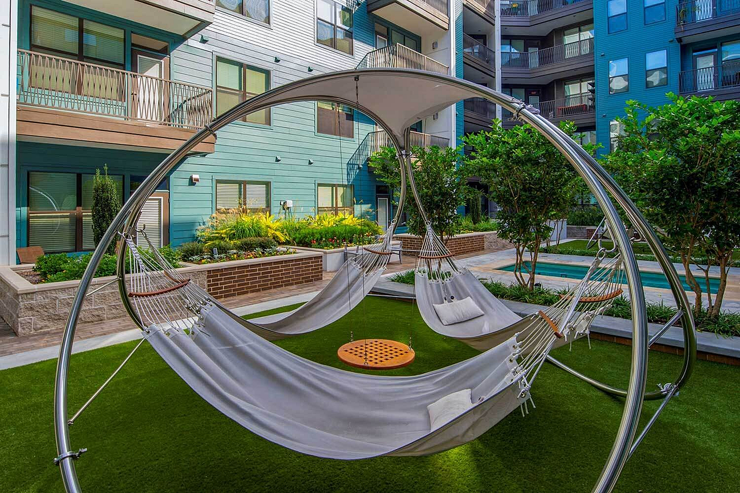 Modern apartment courtyard with inviting hammocks, lush greenery, and stylish architecture.