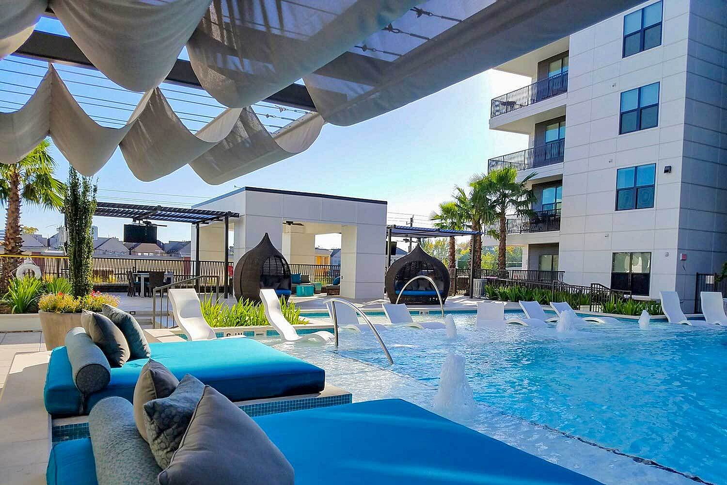 Luxurious apartment complex featuring a chic rooftop pool with stylish lounge chairs, lush greenery, and elegant cabanas, perfect for relaxation and modern living.