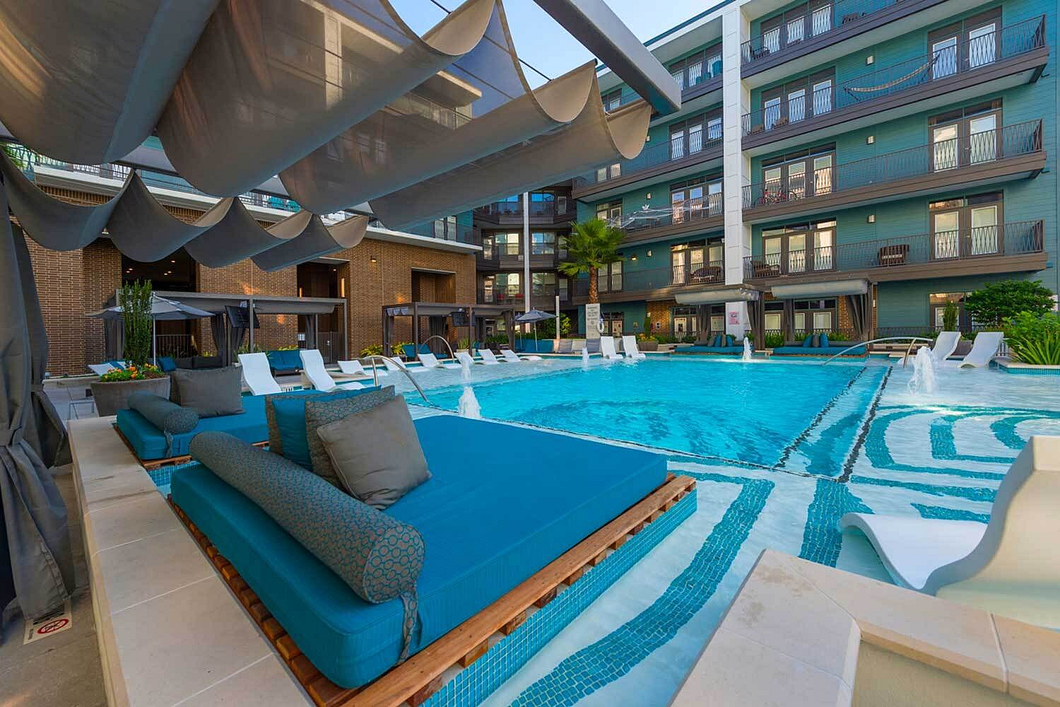 Luxurious apartment complex featuring a stunning pool area with stylish loungers, cozy cabanas, and modern architectural design.