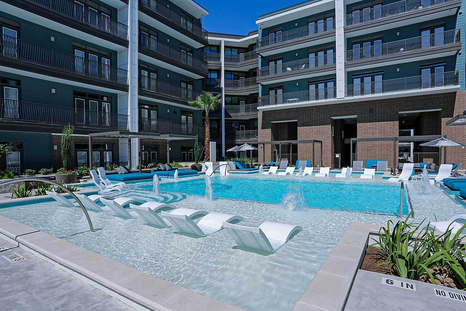 Luxurious apartment complex with modern amenities featuring an inviting resort-style swimming pool with lounge chairs, perfect for relaxation.