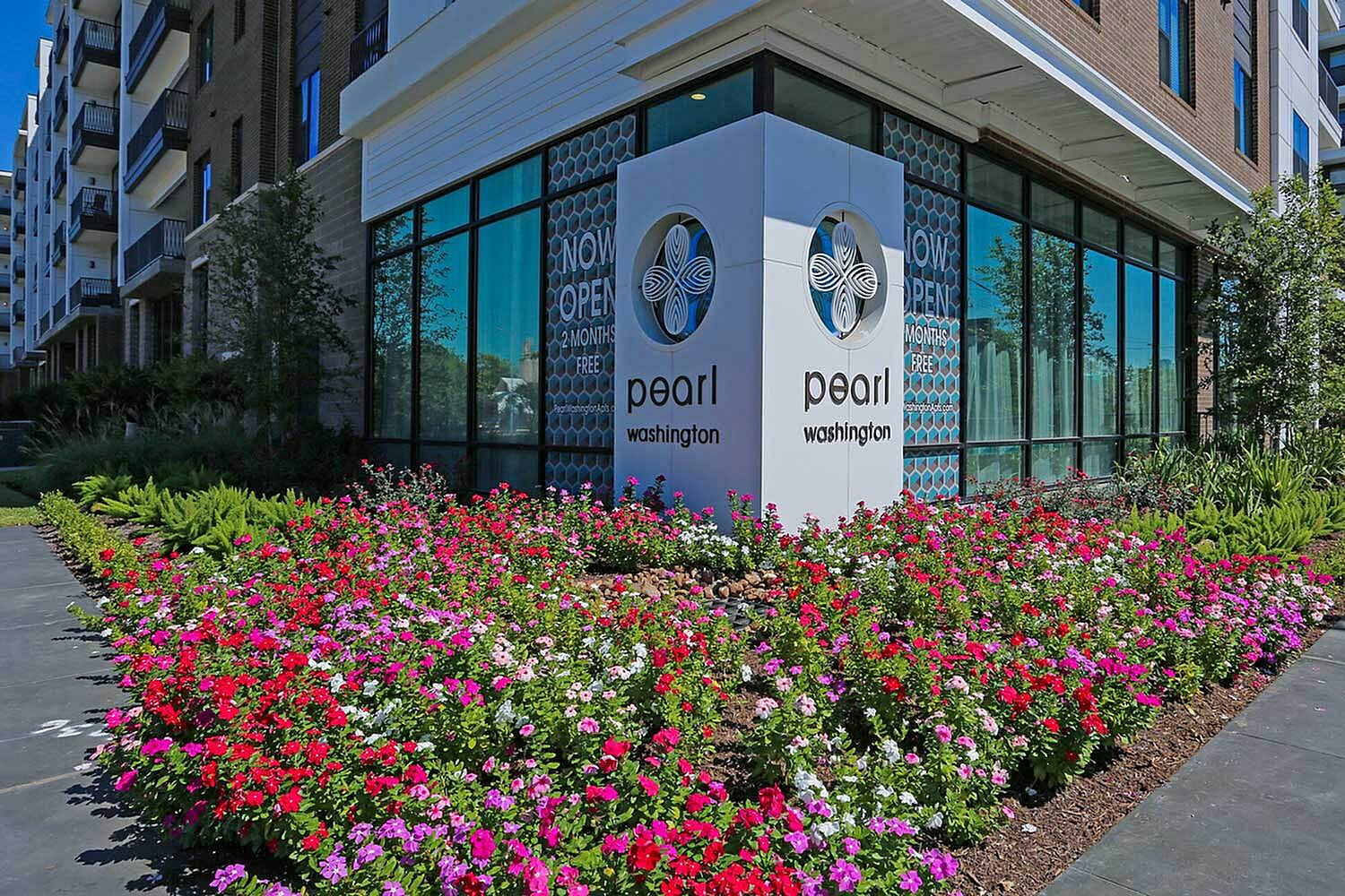 Vibrant corner view of Pearl Washington apartment complex with beautiful flower garden and large welcoming windows.