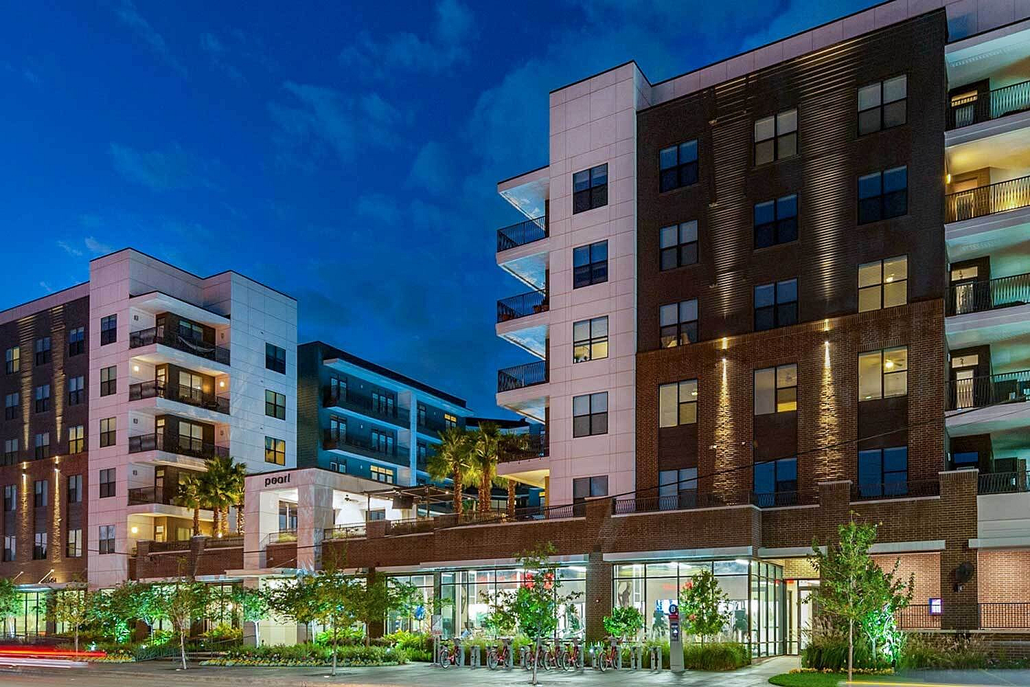 Modern urban apartment building with stylish balconies and vibrant evening lighting.