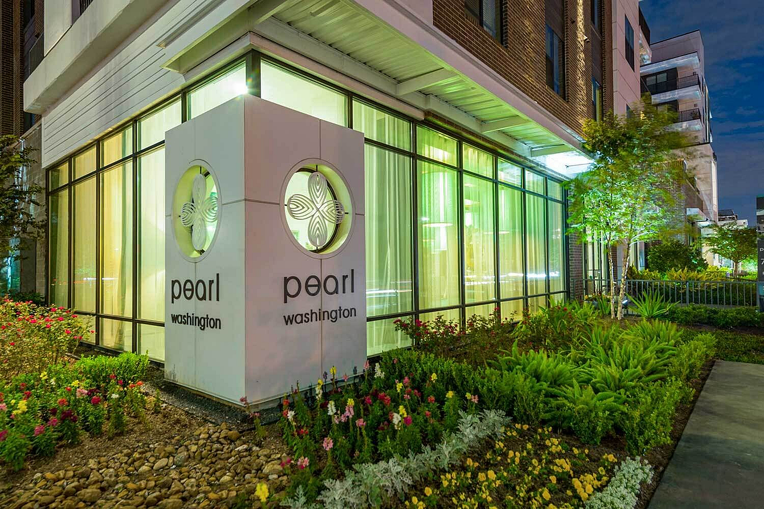 Elegant exterior of Pearl Washington featuring modern architecture and lush landscaping, beautifully illuminated at night.